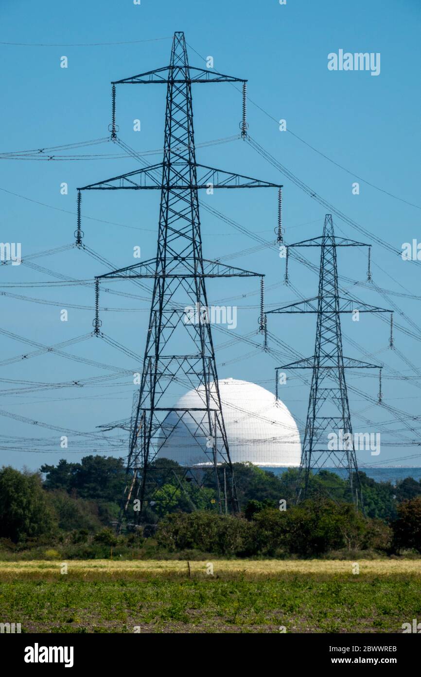 Deux pylônes d'électricité haute tension se tenant devant le dôme de la centrale nucléaire de Sizewell B vu par une brume de chaleur déformant Banque D'Images