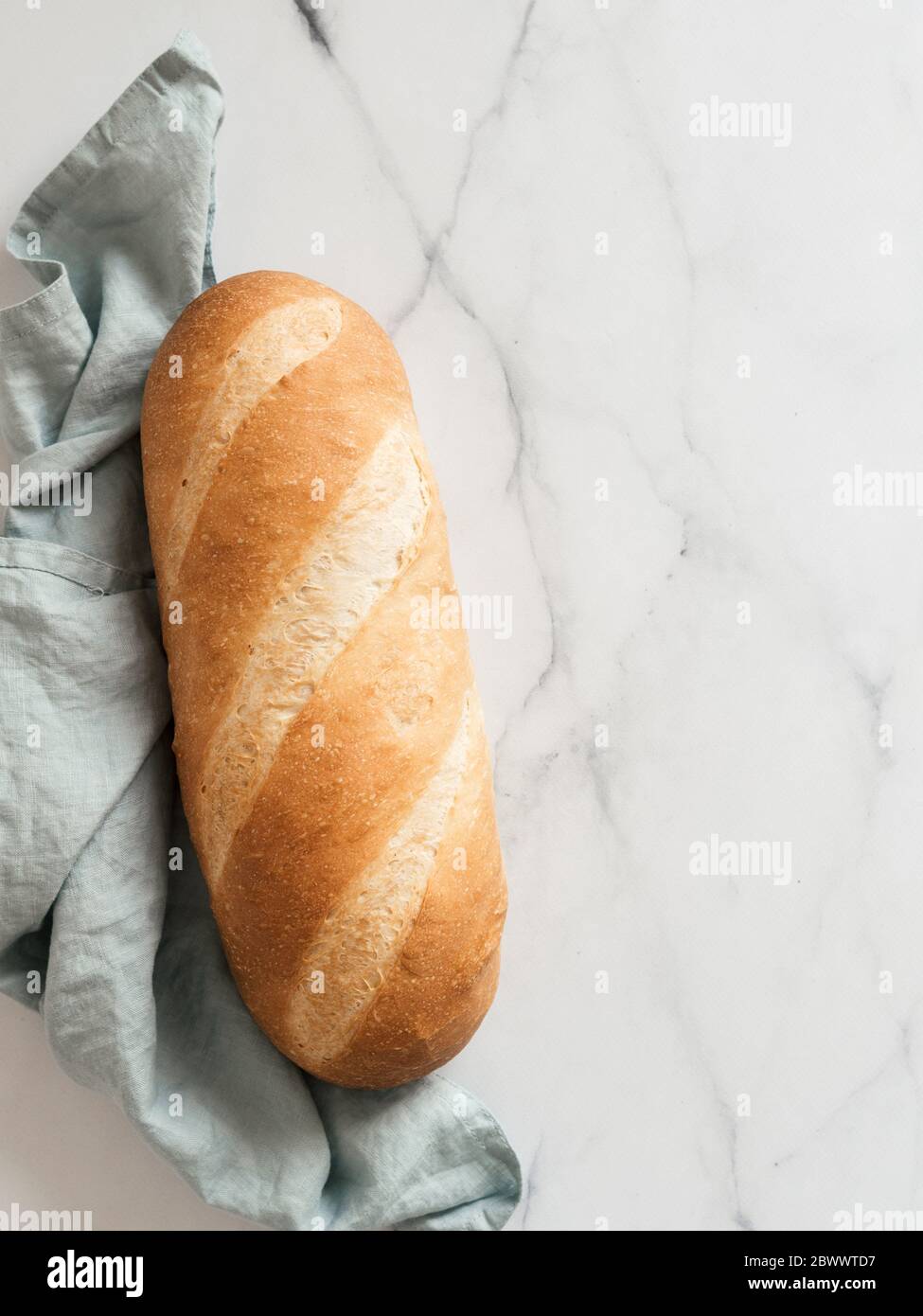 Pain de pain de blomer blanc britannique ou de pain de bâton européen sur fond de marbre blanc. Vue de dessus ou plan d'étapage. Copier l'espace pour le texte ou la conception. Verticale. Banque D'Images