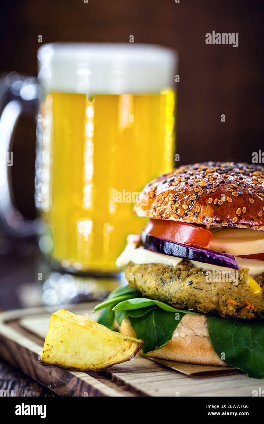 savoureux hamburger végétarien, fait maison sur une table en bois avec des légumes frais et une tasse de bière en arrière-plan, hamburger gastronomique Banque D'Images