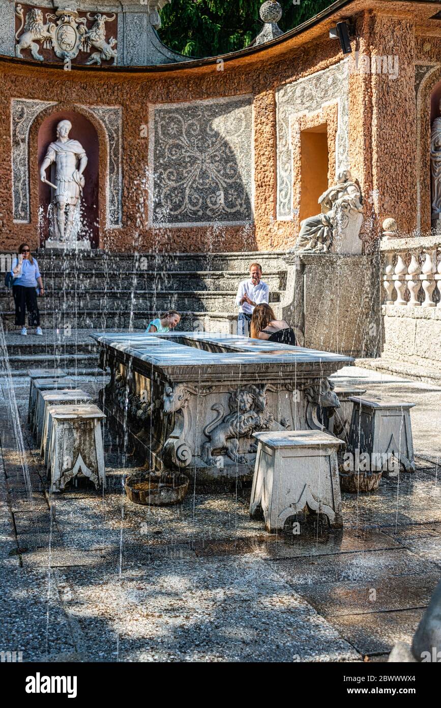 Des fontaines à l'ombre d'une table à dîner et des sculptures sur l'étang dans les jardins publics du palais Hellbrunn (Schloss Hellbrunn) de Salzbourg Banque D'Images