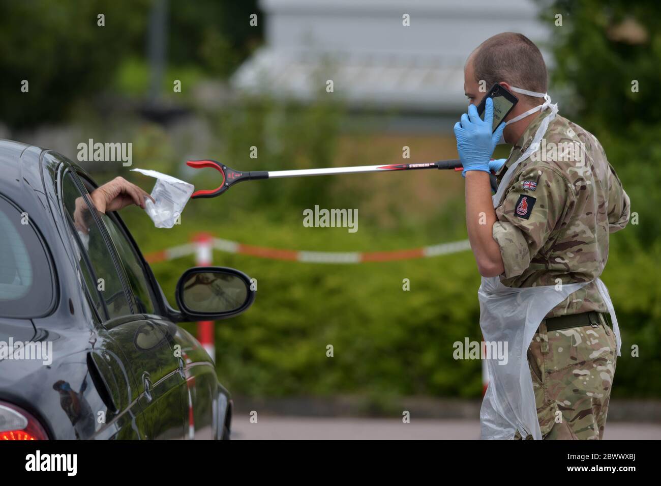 Une personne passe un test automatique complet du coronavirus par une fenêtre de voiture à un réserviste du Royal Anglian Regiment au Harlow football Club, à Harlow, après l'introduction de mesures pour faire sortir l'Angleterre du confinement. Banque D'Images