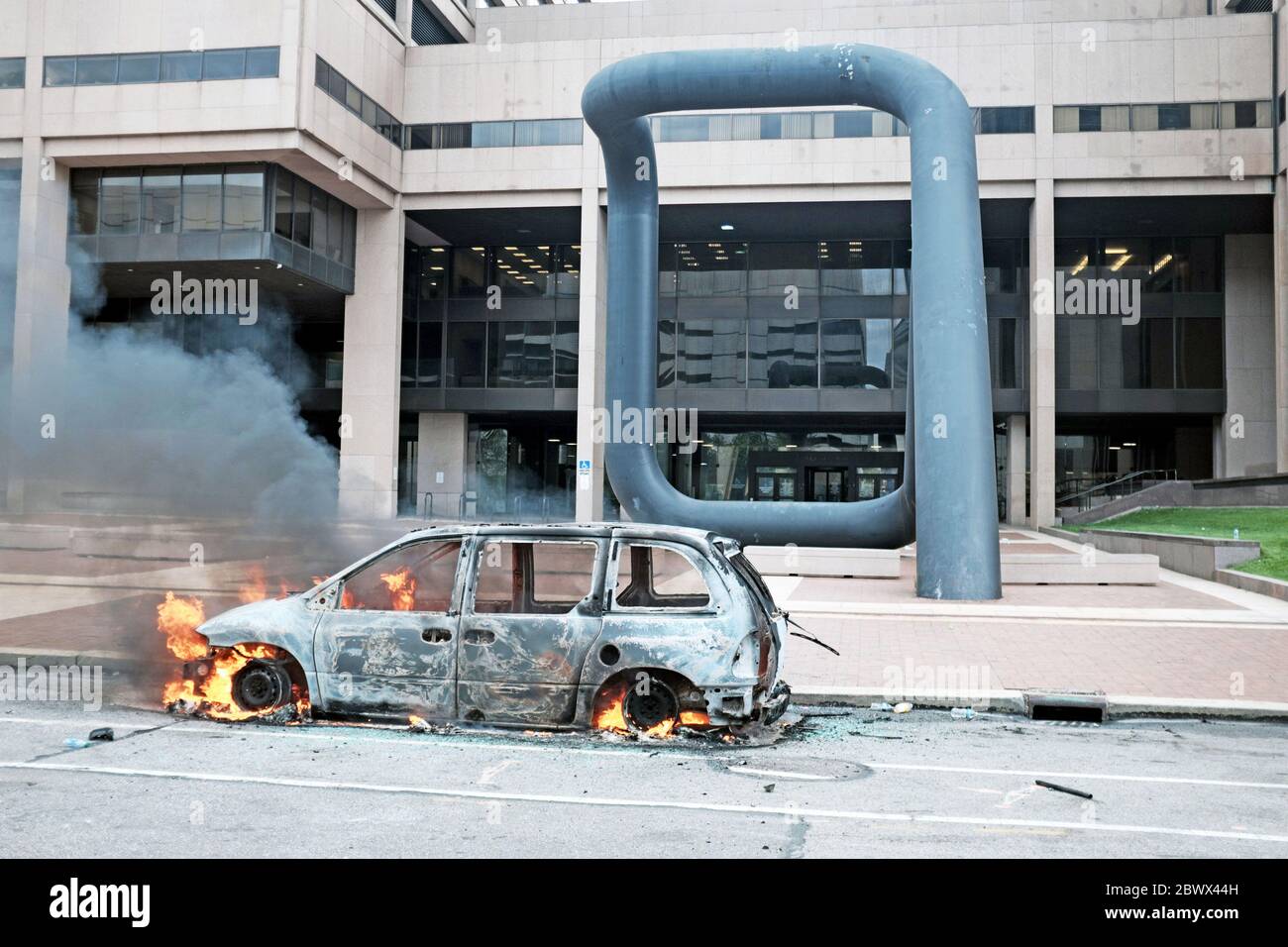 Une voiture brûle sur la rue Ontario à l'extérieur du service de police de Cleveland, au centre-ville de Cleveland, Ohio, États-Unis, lors de manifestations contre le meurtre de George Floyd par la police. L'entrée de la rue Ontario est flanquée de la sculpture d'Isamu Noguchi appelée « Portal, une sculpture de 36 mètres de haut conçue pour refléter « une porte d'espoir ou de désespoir ». Banque D'Images