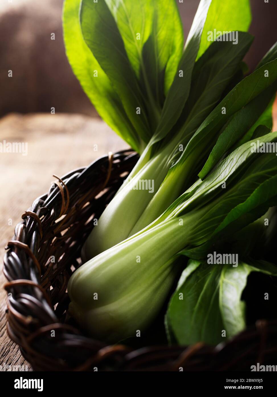 Pak Choi dans un panier en osier sur une table en bois Banque D'Images