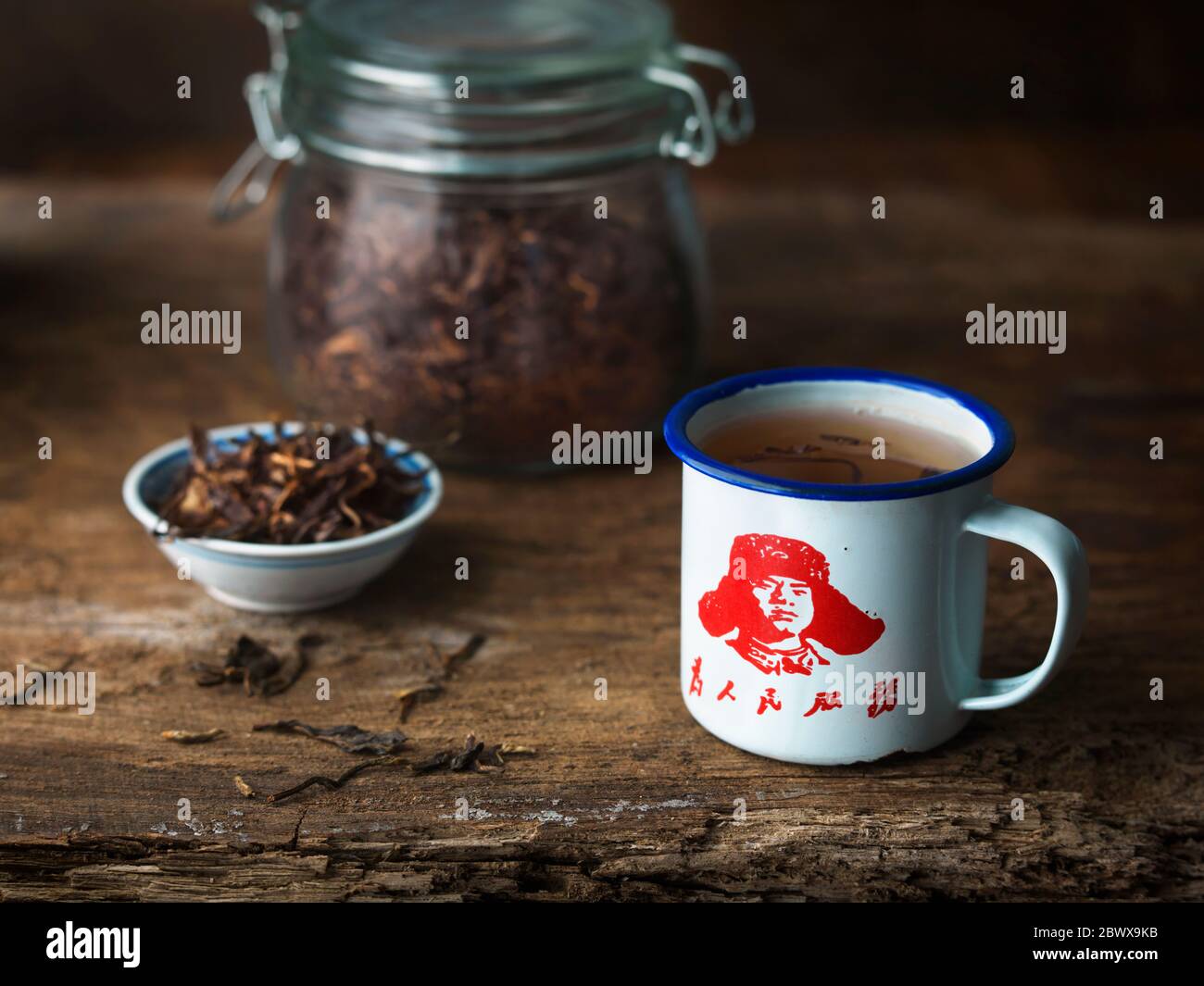 Thé chinois dans un pot en verre et un plat et le président Mao tasse en émail blanc Banque D'Images