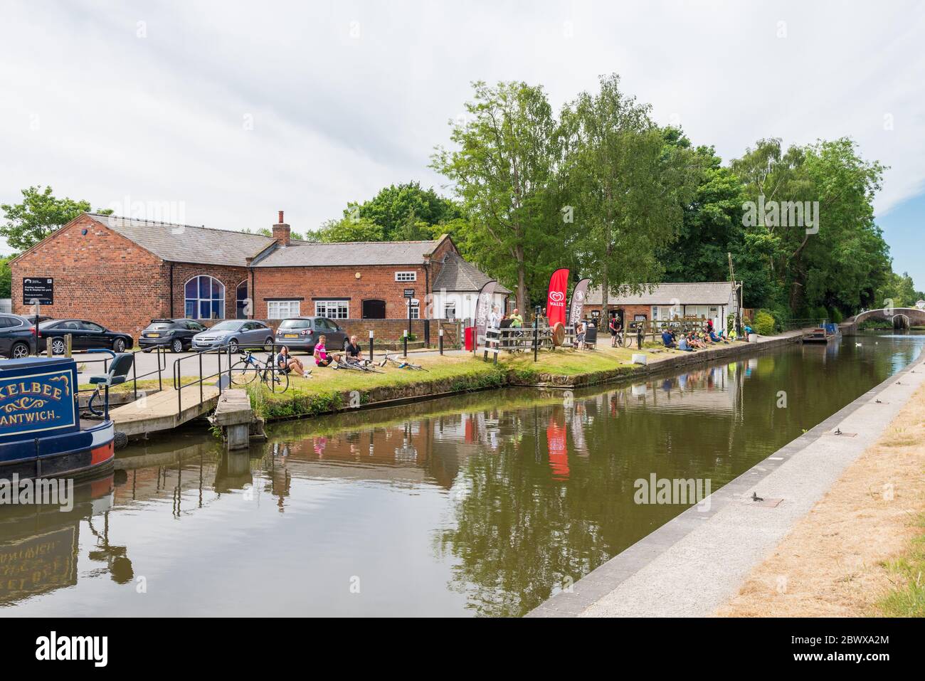 Les visiteurs du café Fradley Canalside à Fradley Junction, dans le Staffordshire, s'assoient sur le bord de l'herbe pour manger et boire Banque D'Images