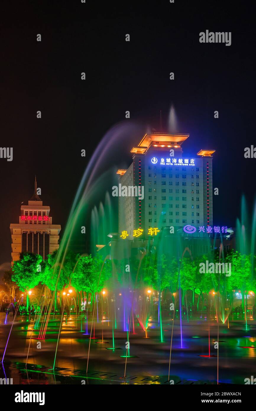 Xian, Chine - 1er mai 2010 : scène de nuit noire. Illuminé HNA Hotel Downtown vu à travers des fontaines colorées et parc d'arbres verts illuminés. Banque D'Images