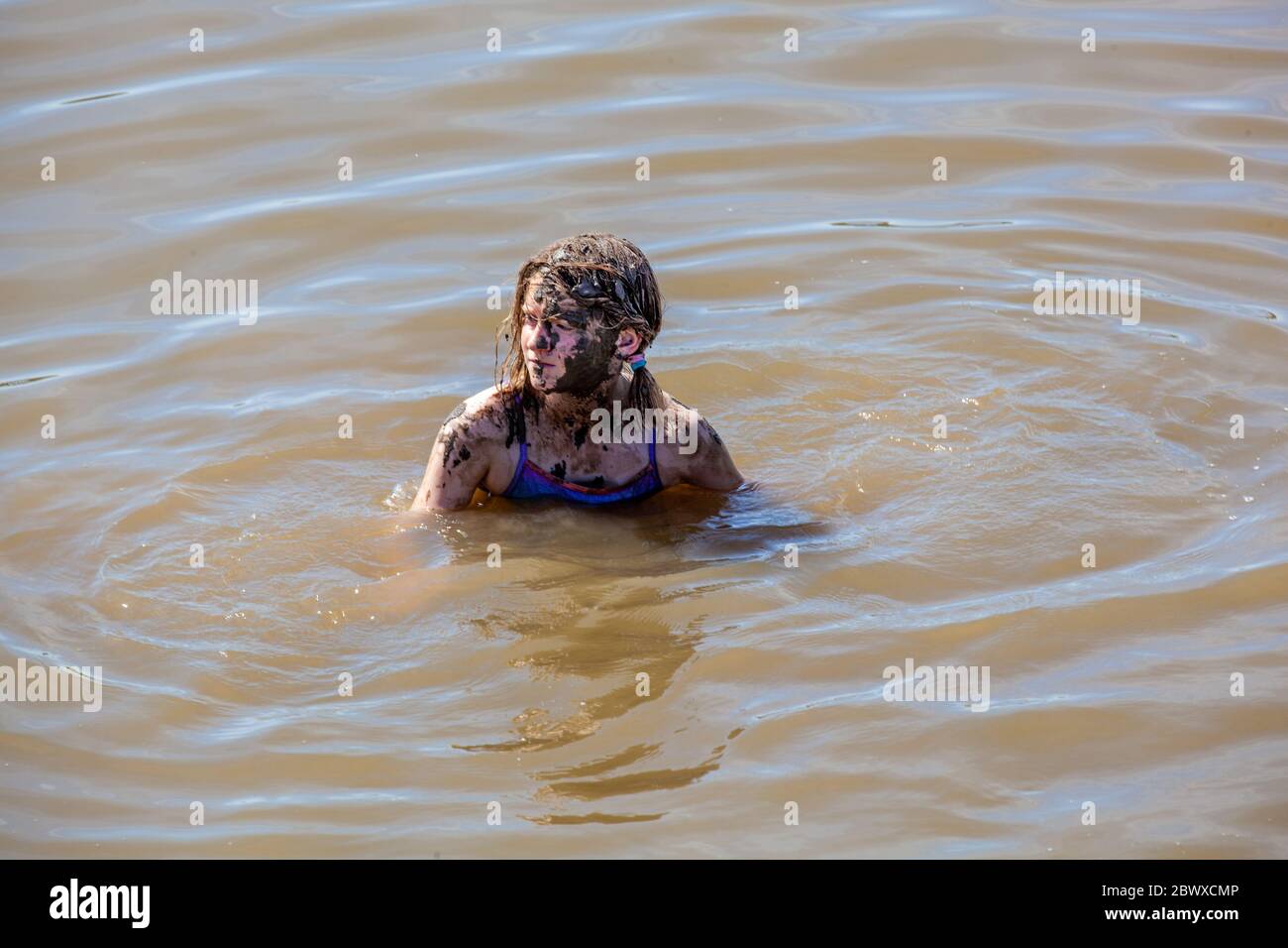 Jeune fille sortie de l'eau au bord de la mer couverte de boue Banque D'Images