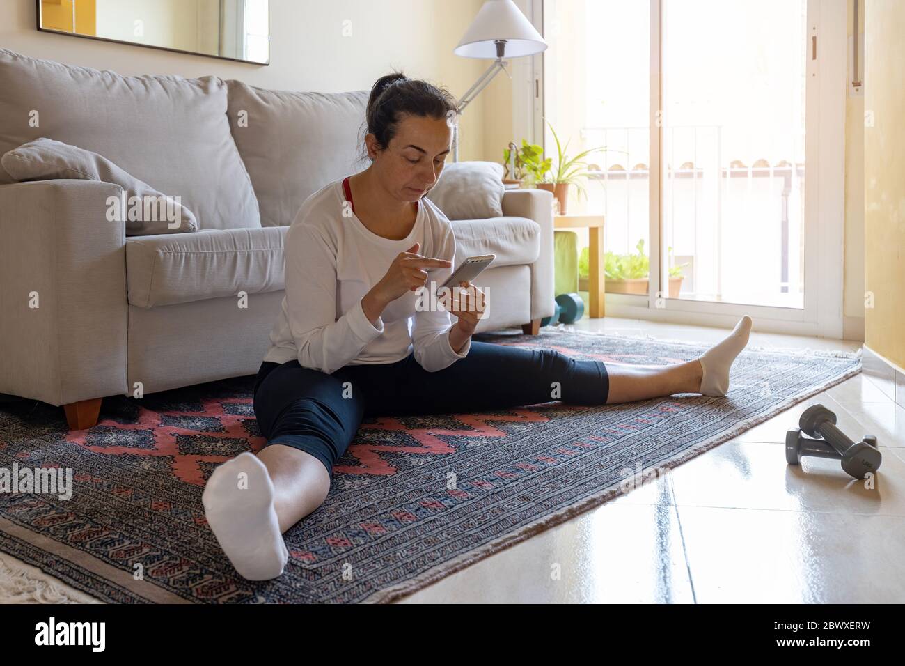 Jolie fille espagnole pratique la gymnastique à la maison dans le salon et faire une pause Banque D'Images
