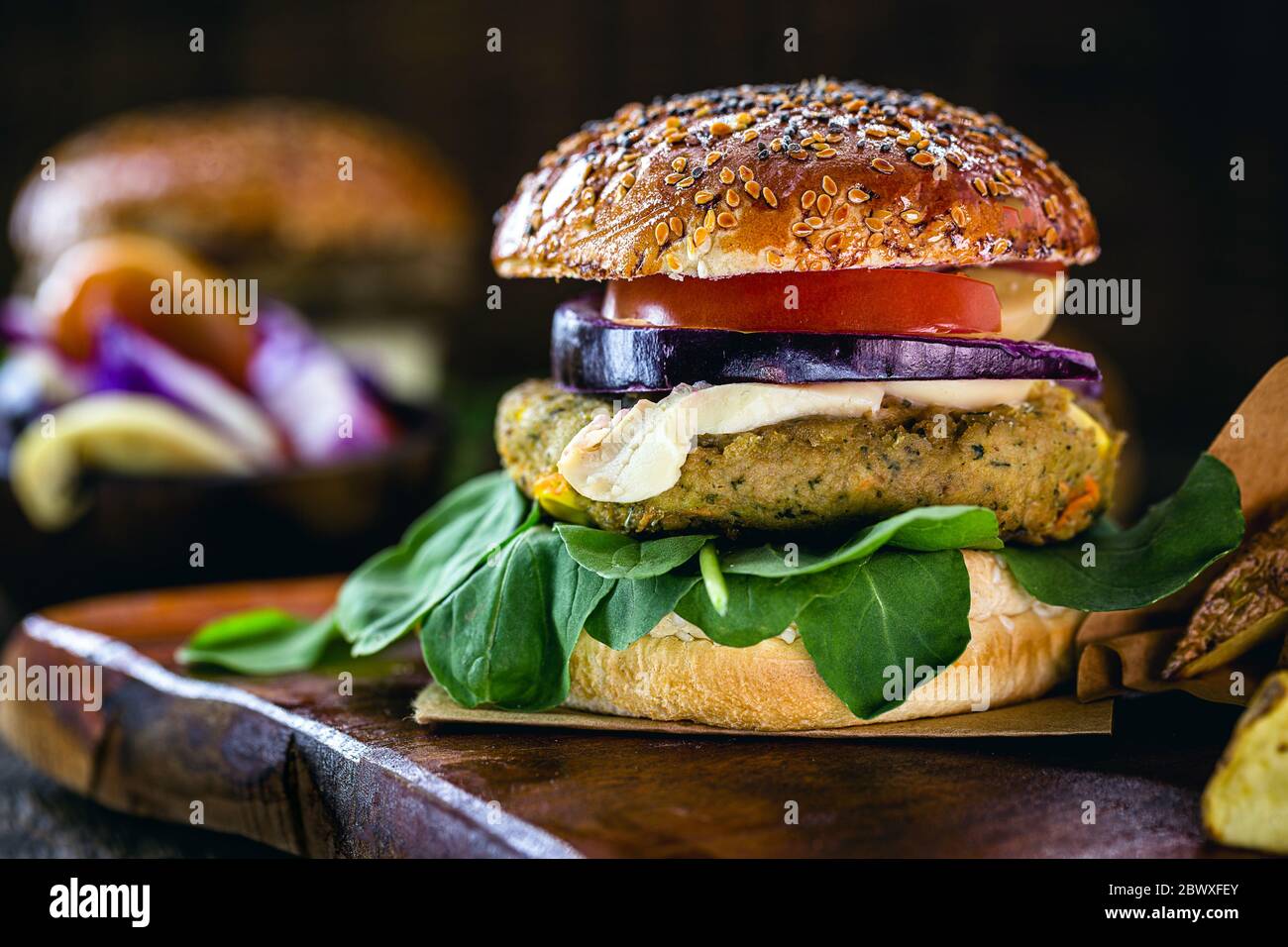 Hamburger végétalien, sandwich fait sans viande, avec un verre de jus de fruits verts en arrière-plan. Sandwich au poivre, aux champignons, à la tomate, à la laitue et aux protéines Banque D'Images