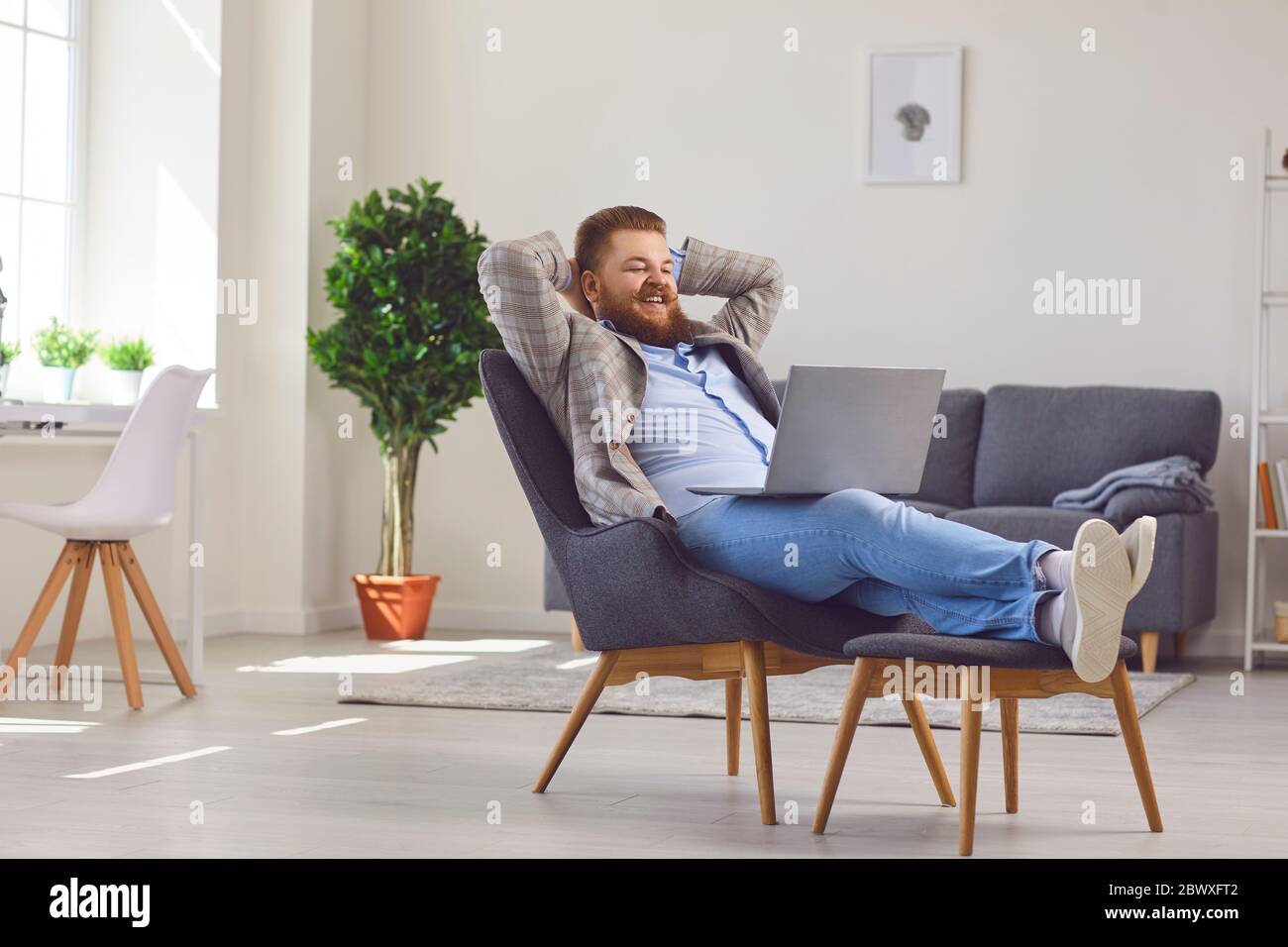Travailler en ligne au bureau à domicile. Drôle gros homme travaillant PC portable en ligne de réunion de chat dans un bureau à la maison. Banque D'Images