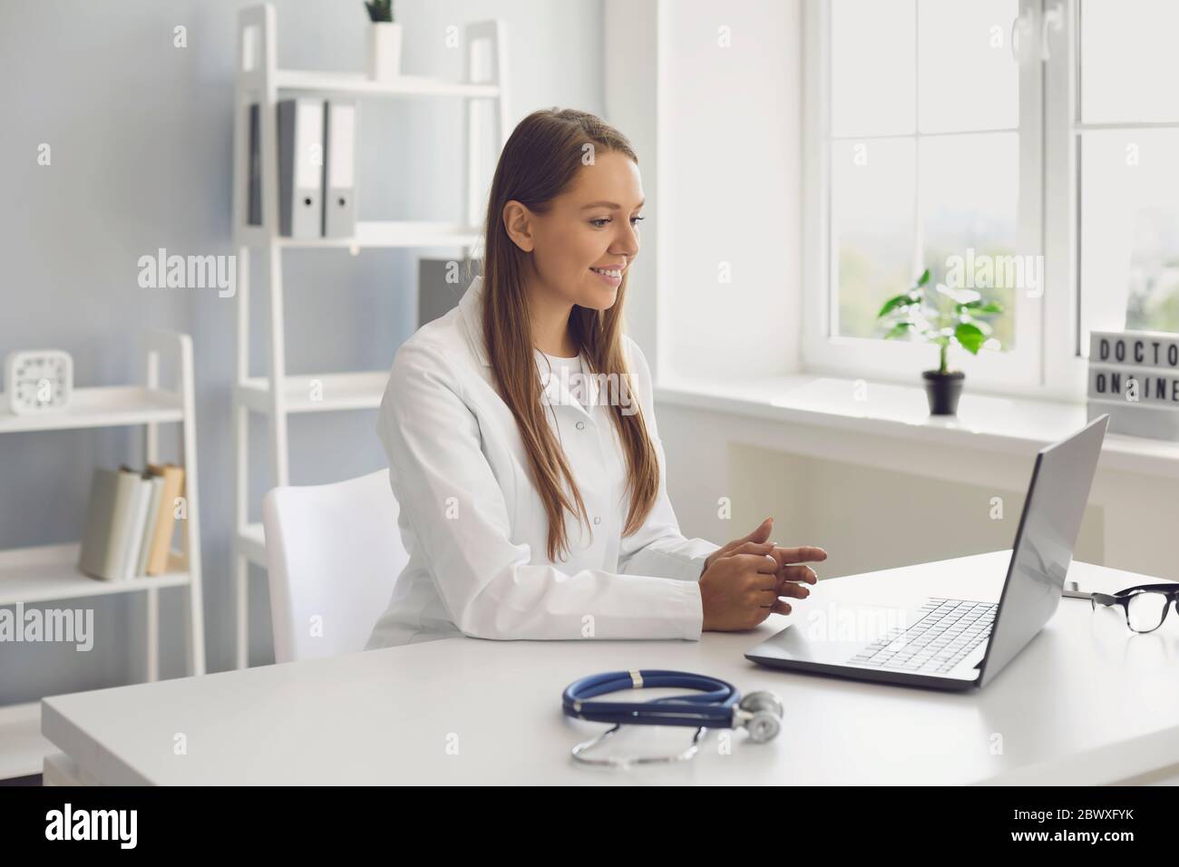 Jeune femme médecin consultant patient en ligne, en utilisant un ordinateur portable à son bureau. Le médecin traitant effectue un appel vidéo au client malade Banque D'Images