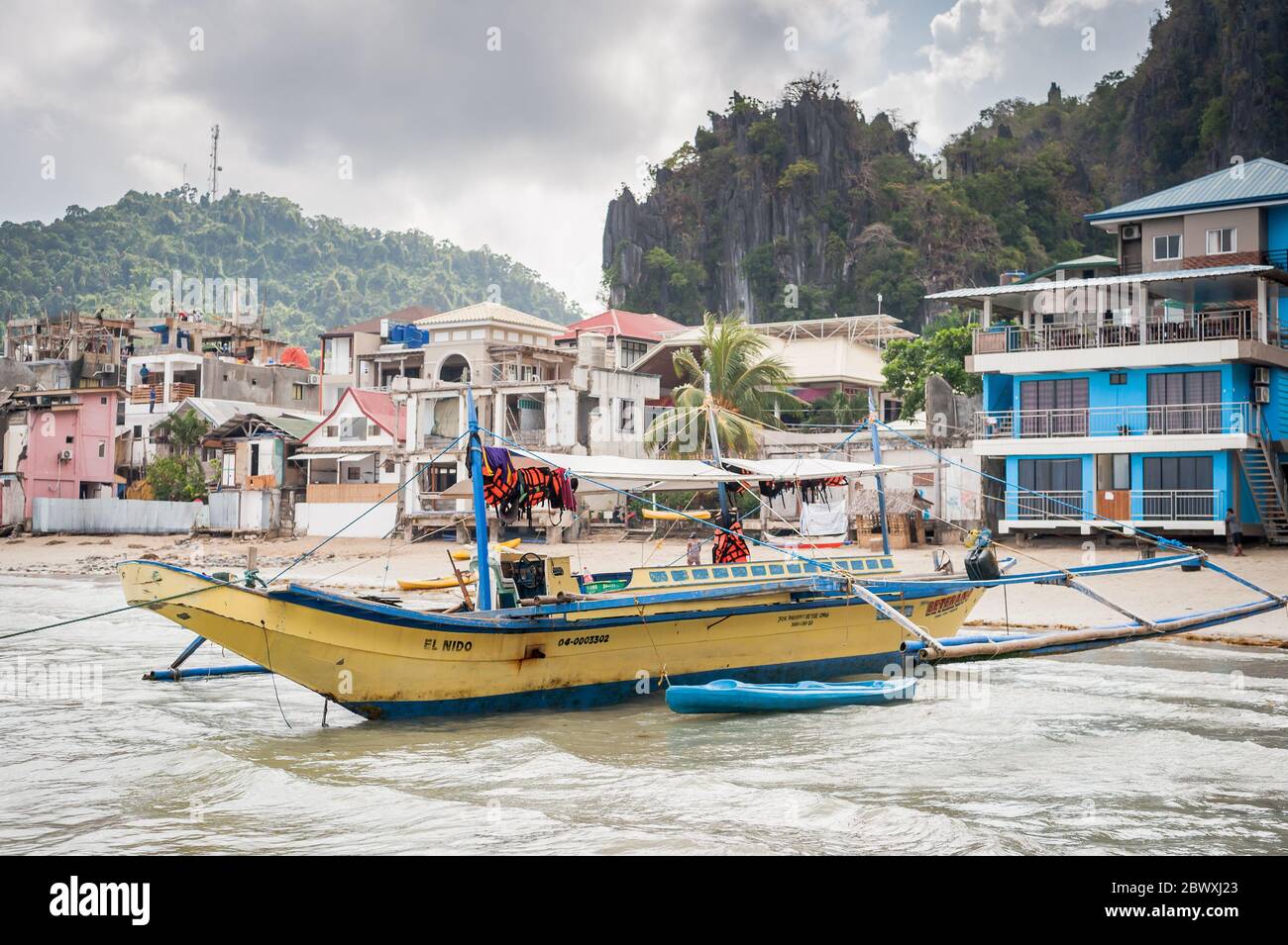 Les bateaux locaux se trouvent juste au large, attendant que les touristes visitent les îles locales à El Nido, Palawan, Philippines. Banque D'Images