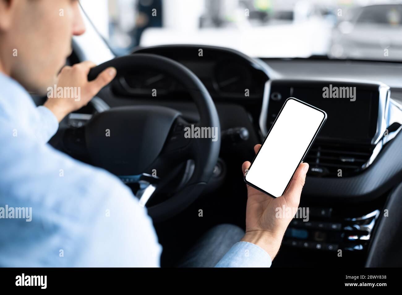 Homme utilisant un smartphone assis en voiture dans Auto Center Banque D'Images
