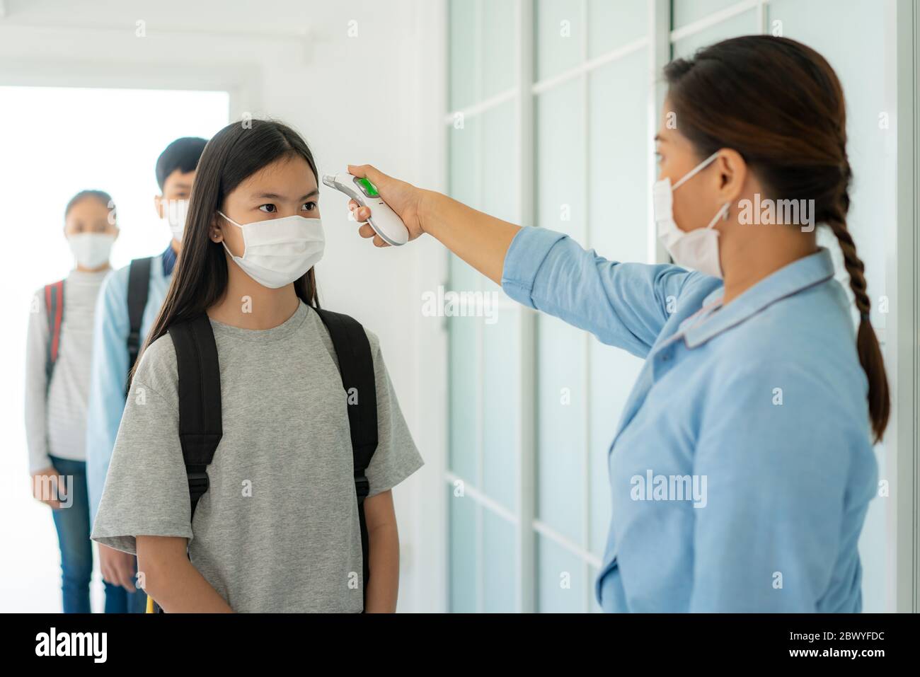 Femme asiatique enseignante utilisant le thermomètre de température de dépistage étudiant pour la fièvre contre la propagation de COVID-19 alors que l'étudiant de retour à l'école, Nouveau Banque D'Images