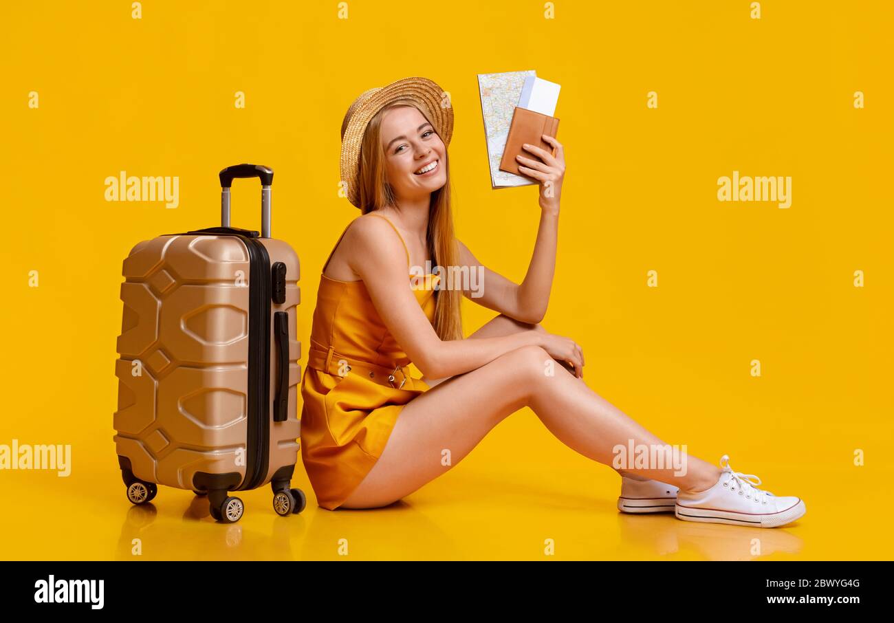 Concept d'assurance voyage. Jeune fille assise sur le sol avec Suitcase et billets Banque D'Images