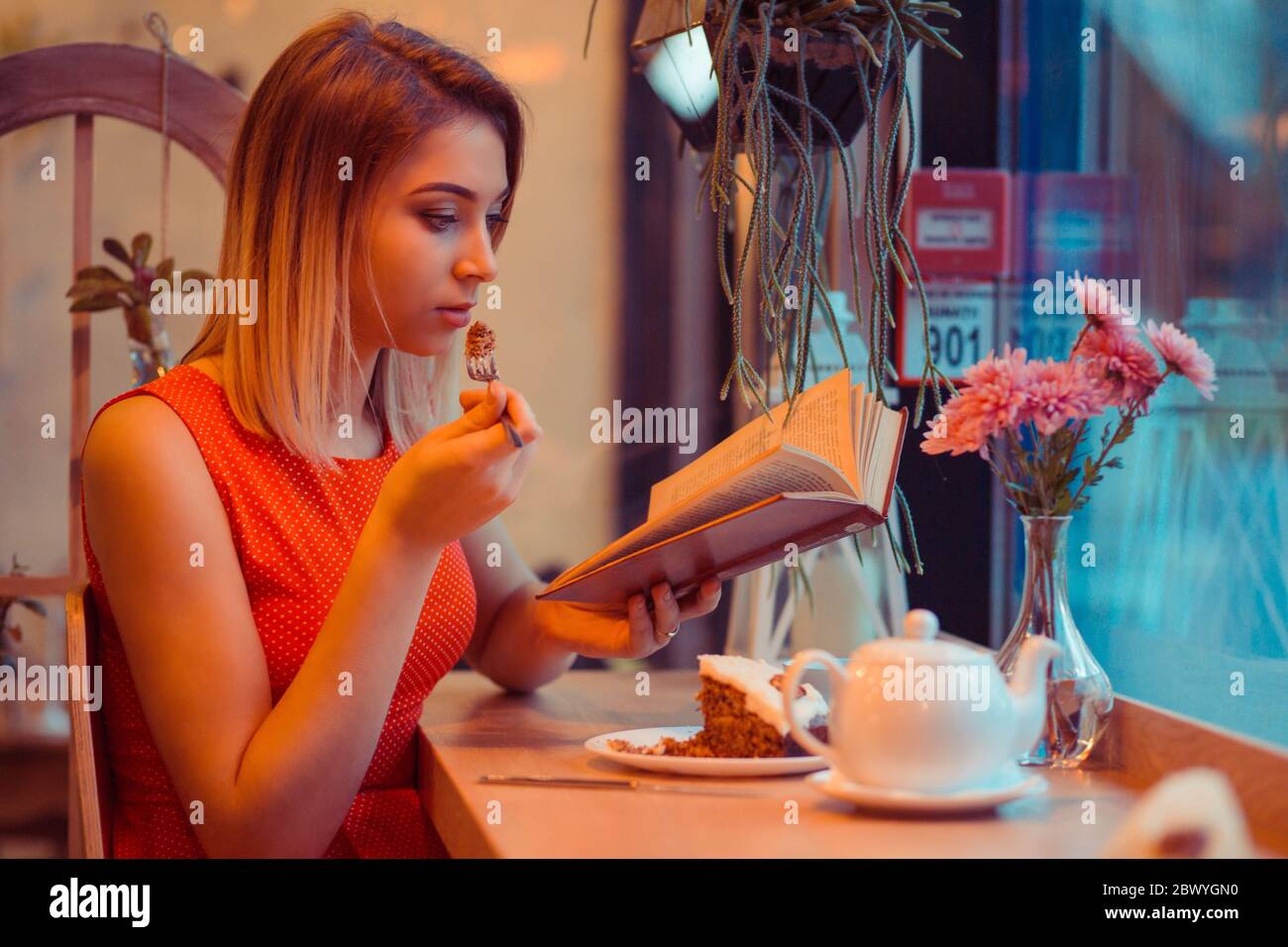 Femme Interessee Voyageur Portant Une Robe Rouge Avec Des Pois Blancs Assis Et Manger Gateau De Dessert Avec Creme Au Chocolat Sur Le Dessus Et Boire Du The Pendant Que R Photo