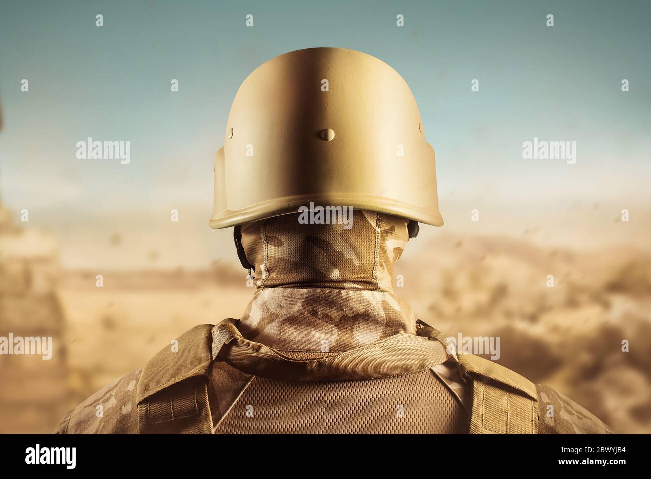 Photo d'un soldat en uniforme de désert debout dans un casque vue arrière sur fond de désert. Banque D'Images