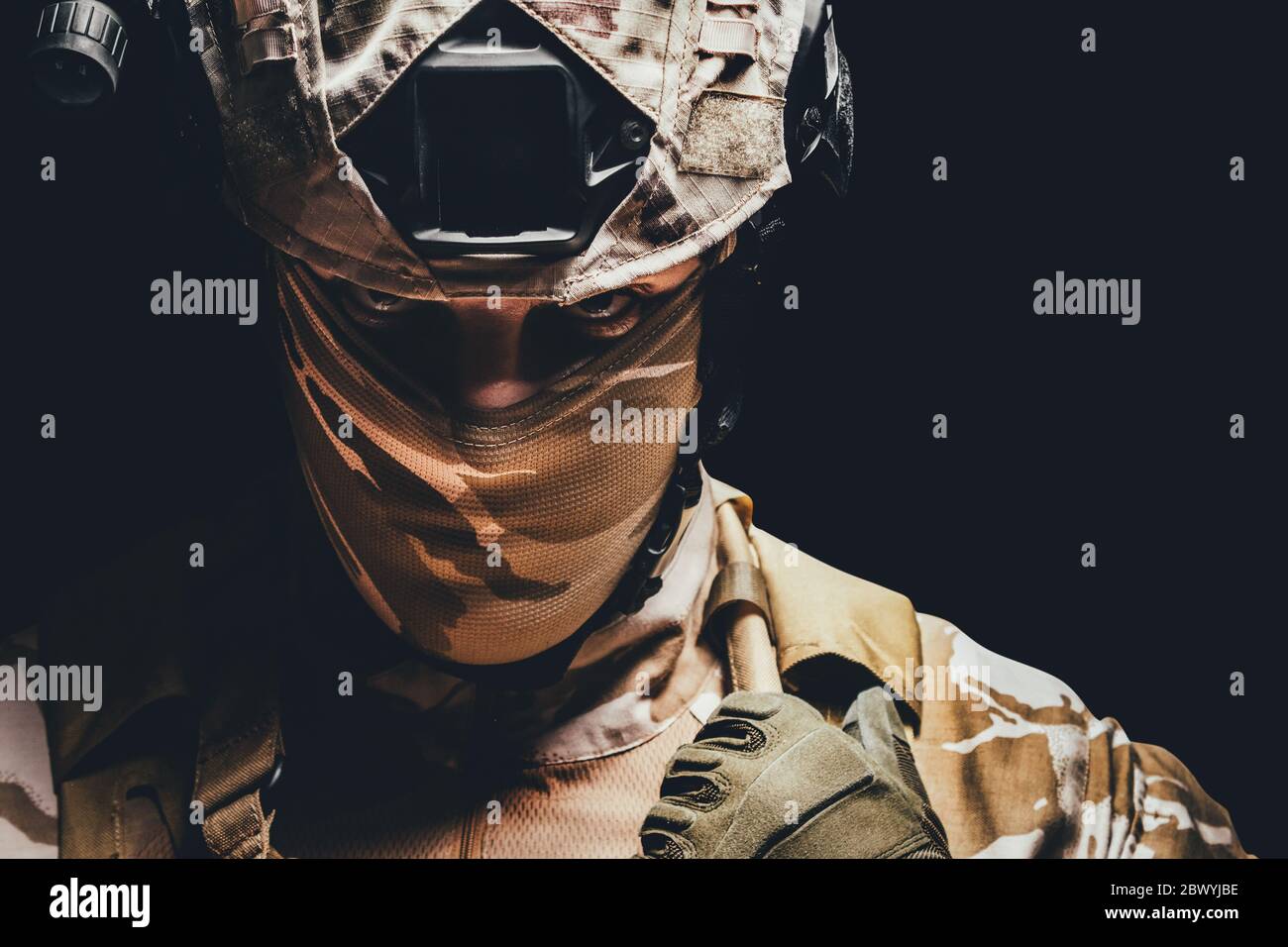 Photo portrait d'un soldat de camouflage du désert entièrement équipé, avec masque, casque et armure sur fond noir. Banque D'Images