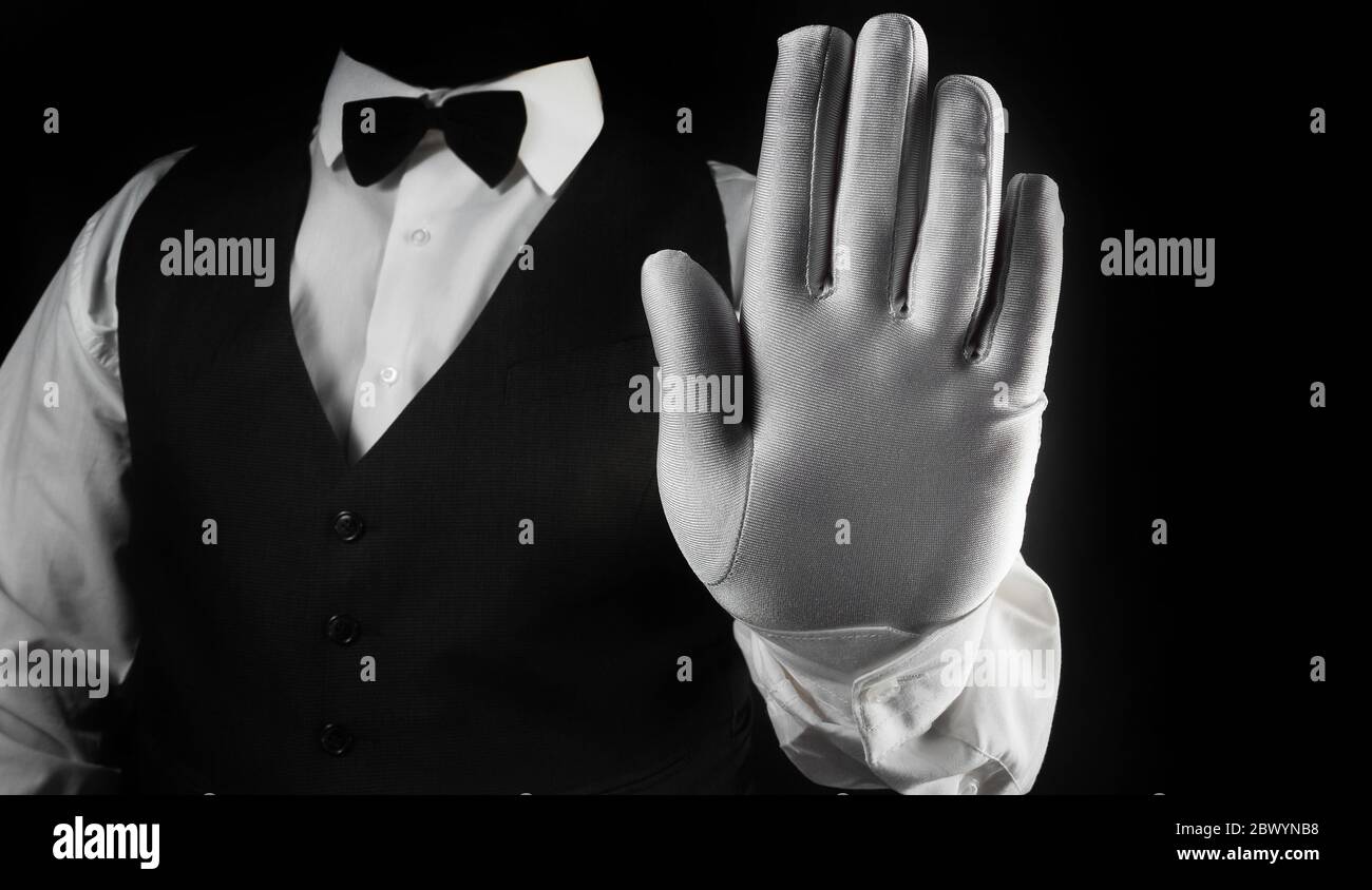 Photo d'un serveur en chemise blanche et gilet noir montrant la paume de la  main en gant blanc sur fond noir vue du torse Photo Stock - Alamy