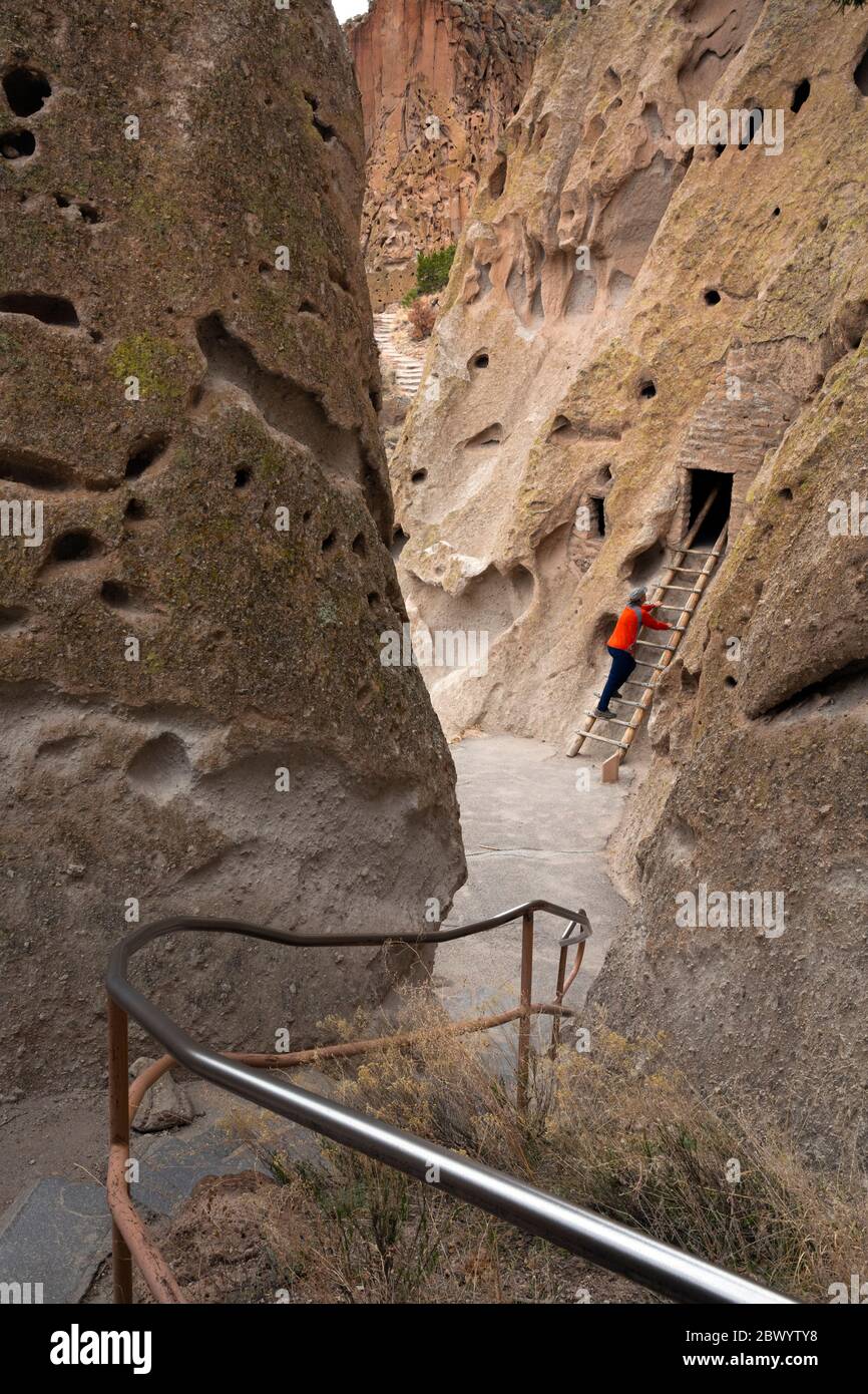 NM00462-00...NOUVEAU-MEXIQUE - visiteur du parc qui visite une habitation sur une falaise vue depuis la piste Loop au monument national de Bandelier. Banque D'Images