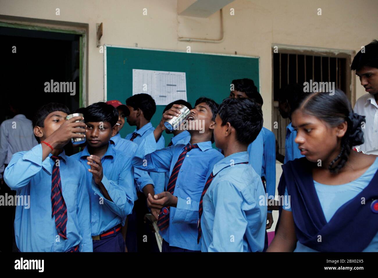 École et dortoir gratuits à Dungeshwari, Bihar, Inde - les élèves de l'école technique de Sujata se tournent pour boire des suppléments nutritionnels fournis par les enseignants après un briefing quotidien après les cours. Banque D'Images
