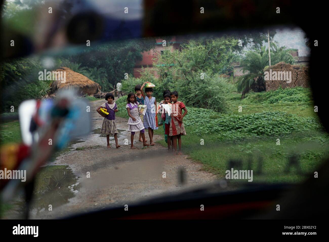 Les enfants se préparent à donner de l'espace à un autorickshaw se déplaçant sur la route rurale menant au village de Dungeshwari à Bihar, en Inde, où la société Join Together dirige Sujata Academy, un complexe scolaire et dortoir gratuit qui a construit comme une aide dans l'éducation des enfants ruraux. Selon les statistiques de l'UNESCO, le nombre d'enfants non scolarisés en Inde s'élevait en 2013 à plus de 2 millions (hommes) et près de 1 millions (femmes). Le Bihar est l'un des États les plus pauvres de l'Inde. Banque D'Images