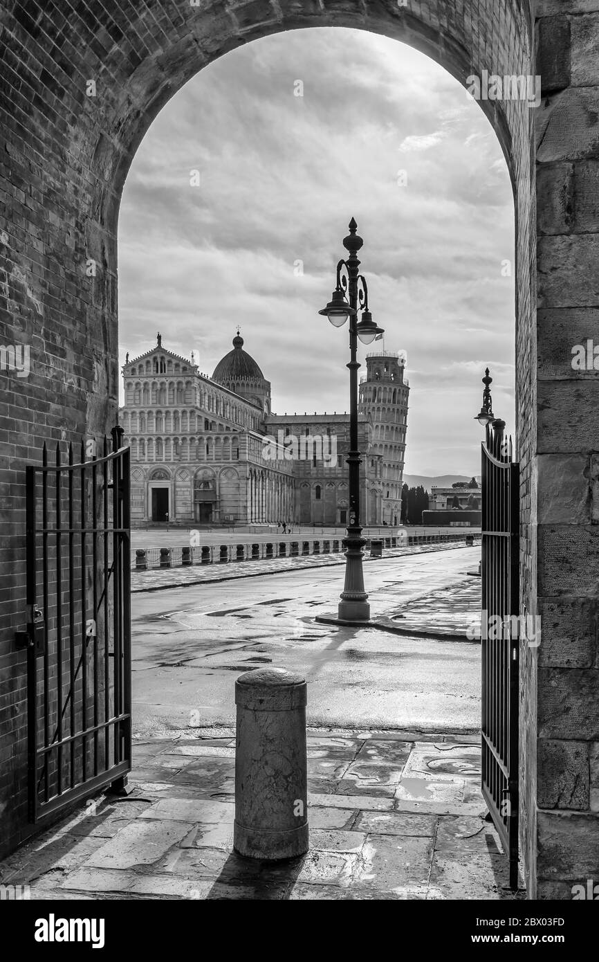 Vue en noir et blanc de la célèbre place Piazza dei Miracoli et de la tour penchée, dans le centre historique de Pise, en Italie, encadrée dans une arche Banque D'Images
