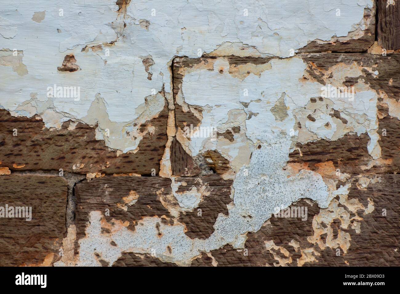 Gros plan de différentes couches de plâtre blanc tombant d'un vieux mur de briques de grès Banque D'Images