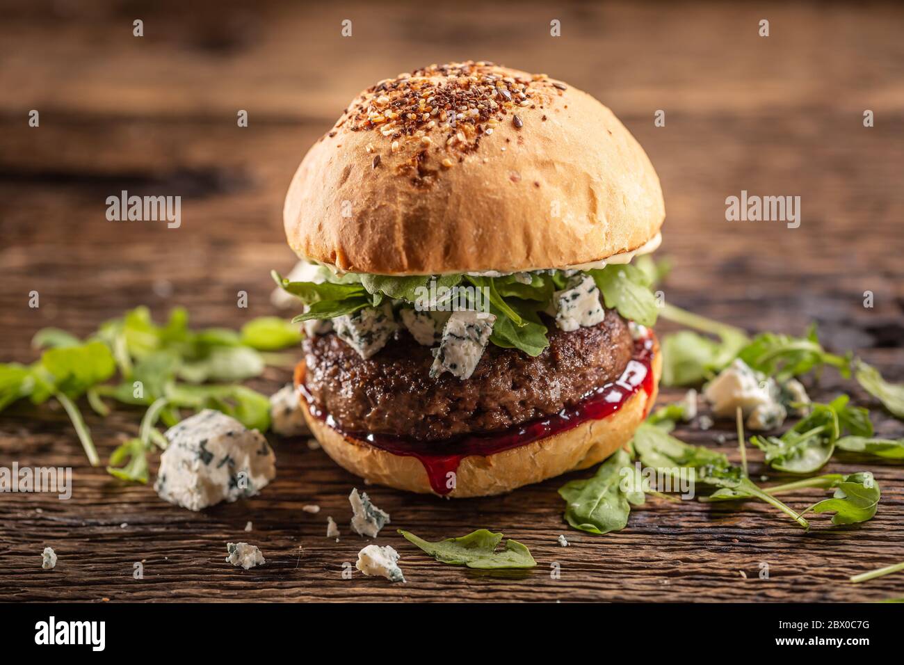 Hamburger de bœuf avec arugula, fromage bleu et sauce aux canneberges dans un pain au sésame Banque D'Images