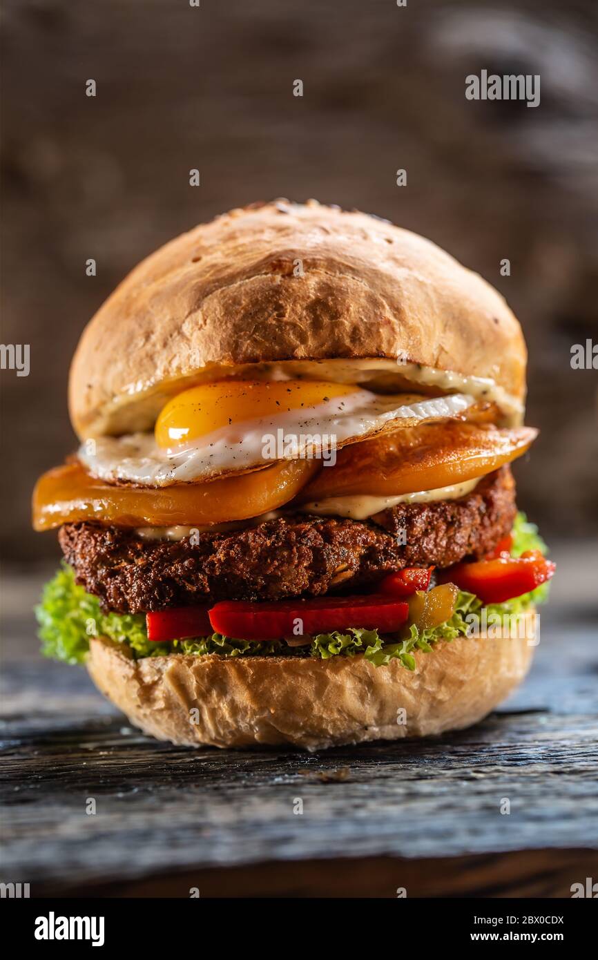 Hamburger végétarien aux haricots avec fromage double, œuf frit, poivrons et salade Banque D'Images