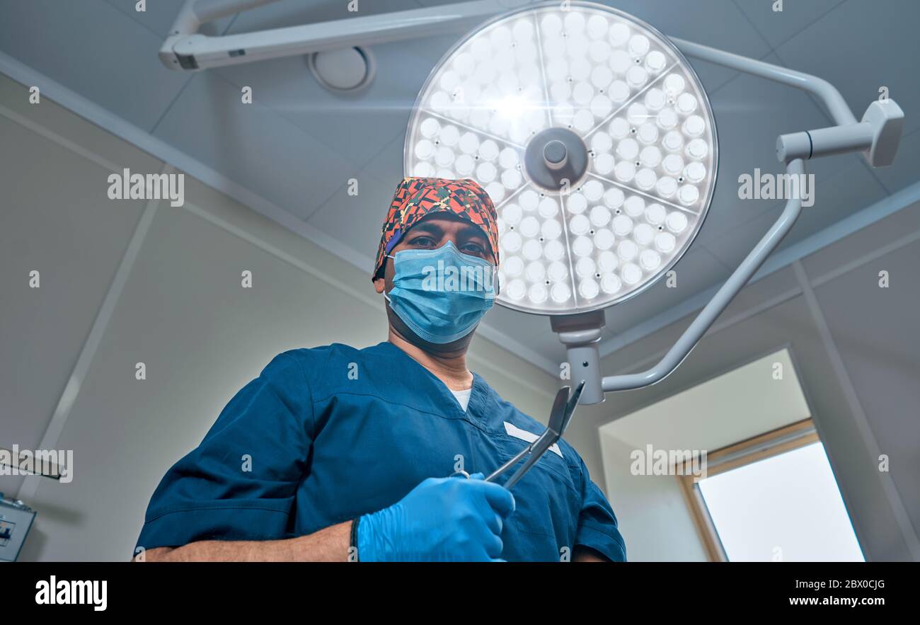 un chirurgien masqué contre une lampe dans la salle d'opération Banque D'Images