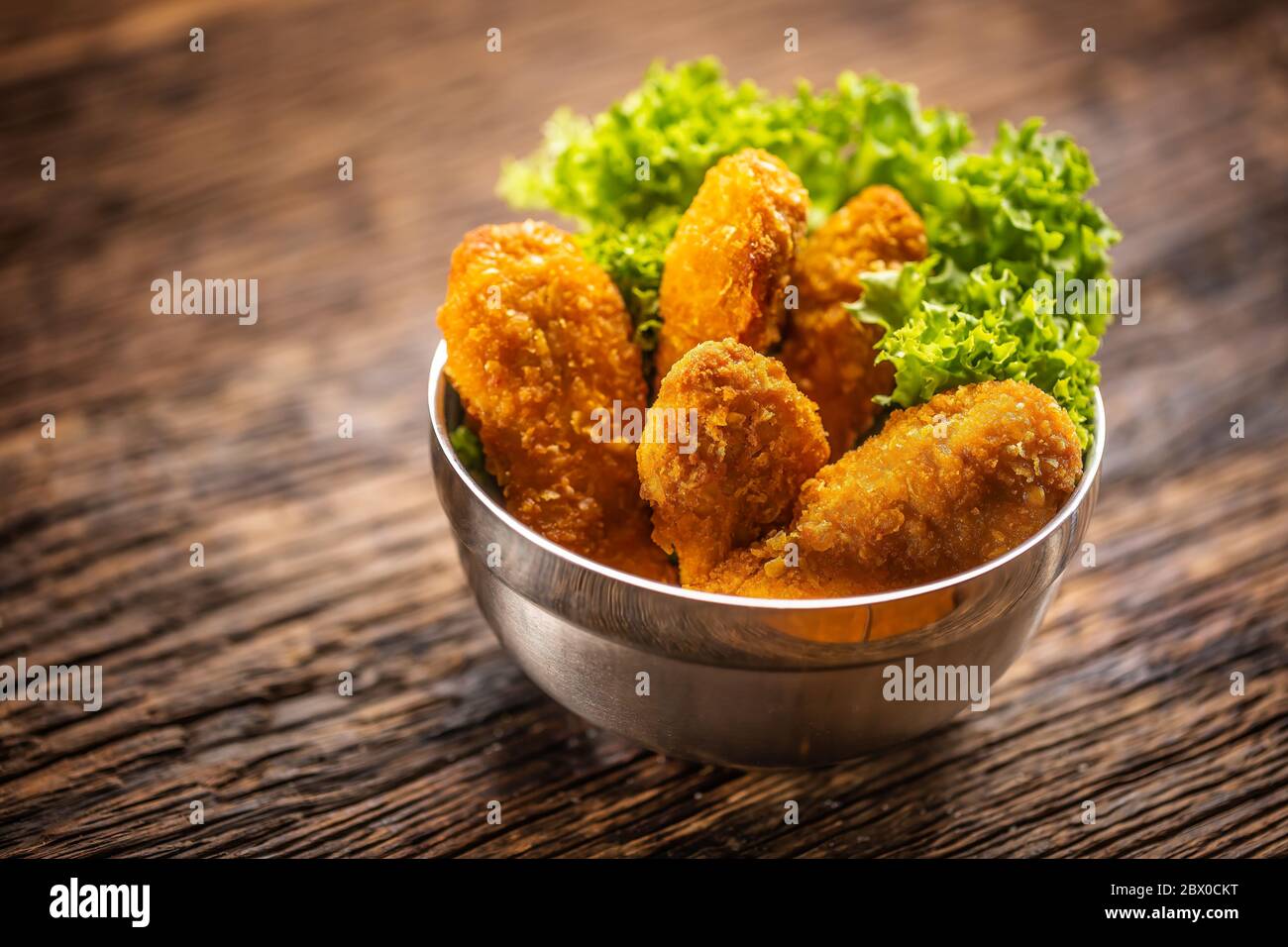 Nuggets de poulet avec salade dans un bol en métal sur une surface rustique en bois Banque D'Images
