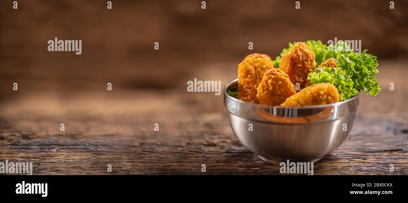 Nuggets de poulet avec salade dans un bol en métal sur une surface rustique en bois Banque D'Images
