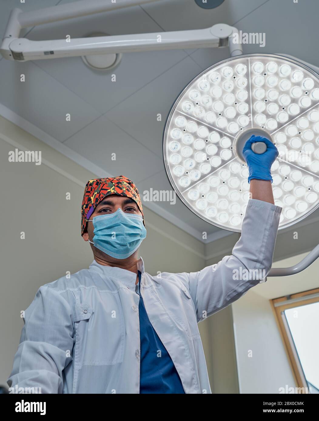 un chirurgien masqué contre une lampe dans la salle d'opération Banque D'Images