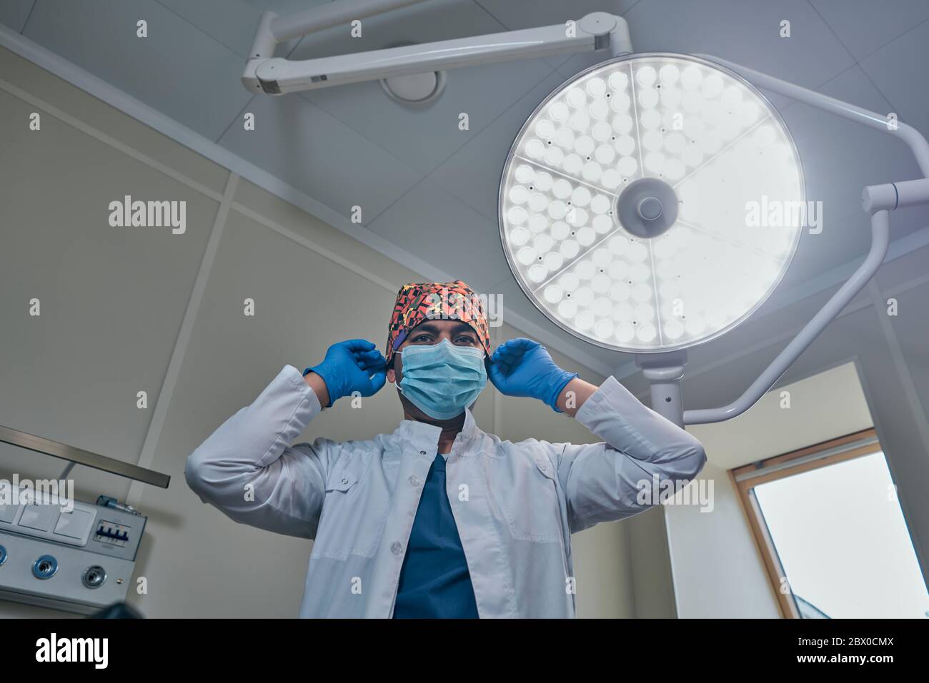 un chirurgien masqué contre une lampe dans la salle d'opération Banque D'Images