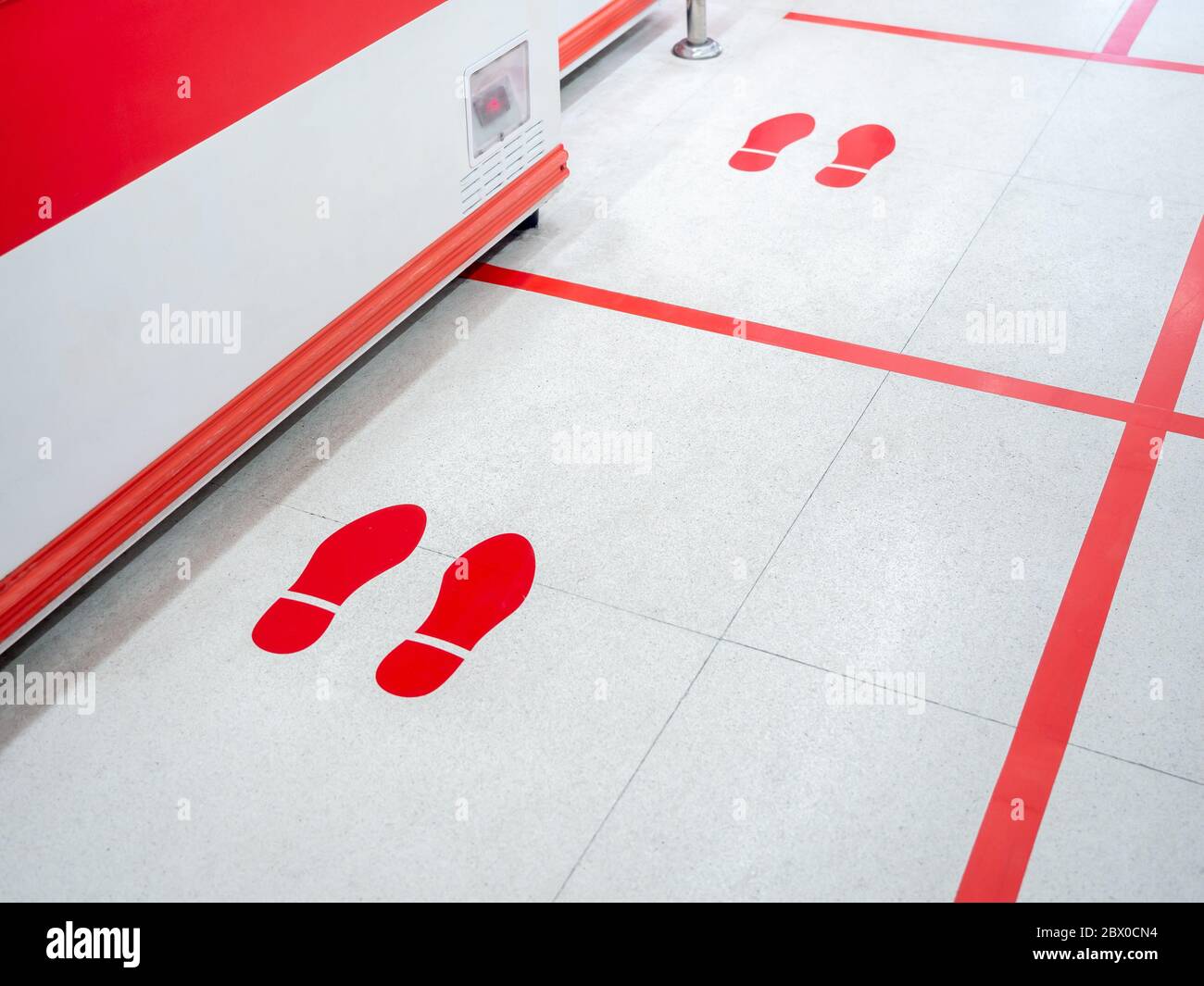 Empreinte rouge et ligne rouge au sol dans le supermarché pour l'avertissement pour garder une distance sociale sûre à protéger contre le coronavirus, concept de distance sociale. Banque D'Images