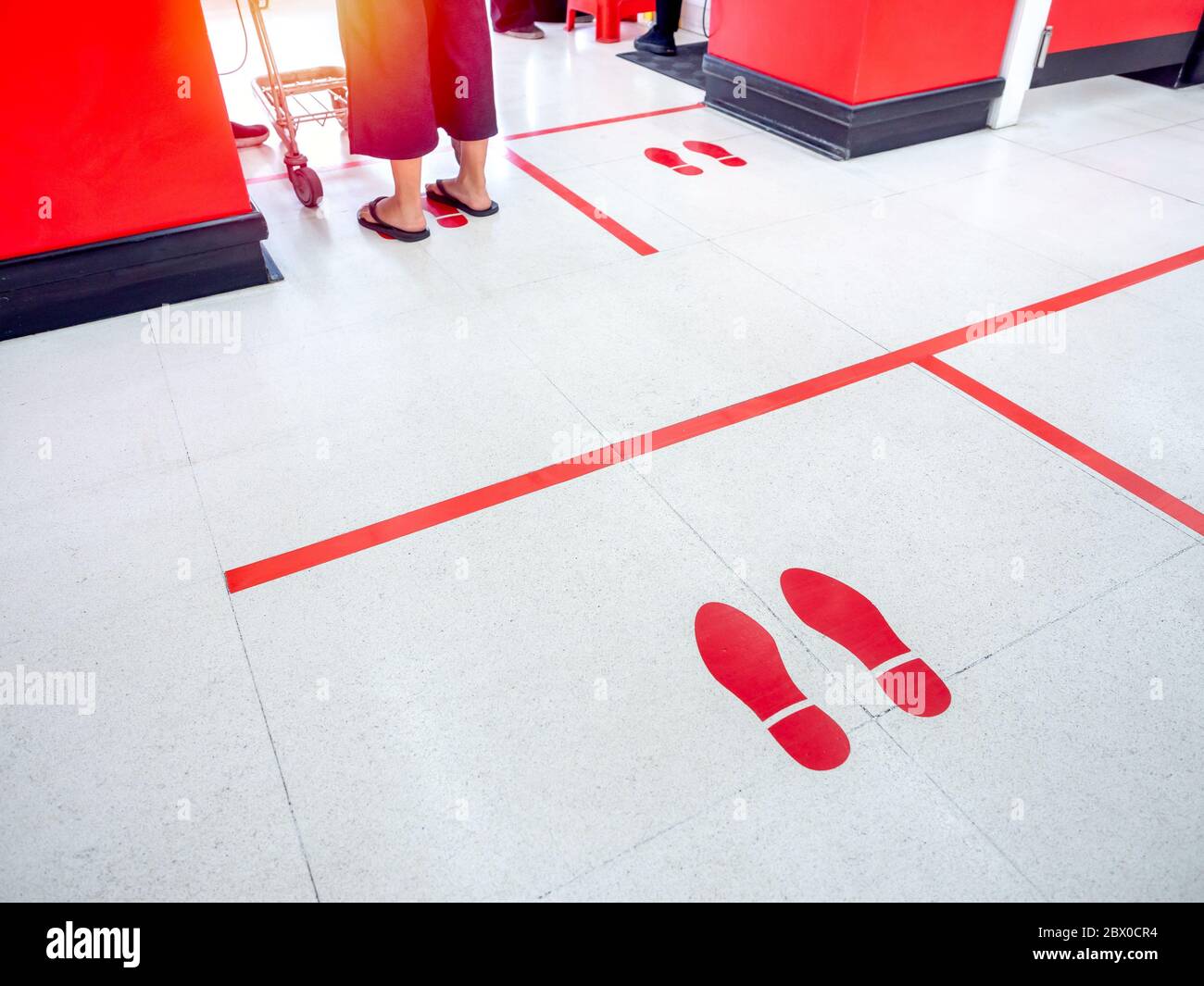 Empreinte rouge et ligne rouge au sol dans le supermarché pour l'avertissement pour garder une distance sociale sûre à protéger contre le coronavirus, concept de distance sociale. Banque D'Images
