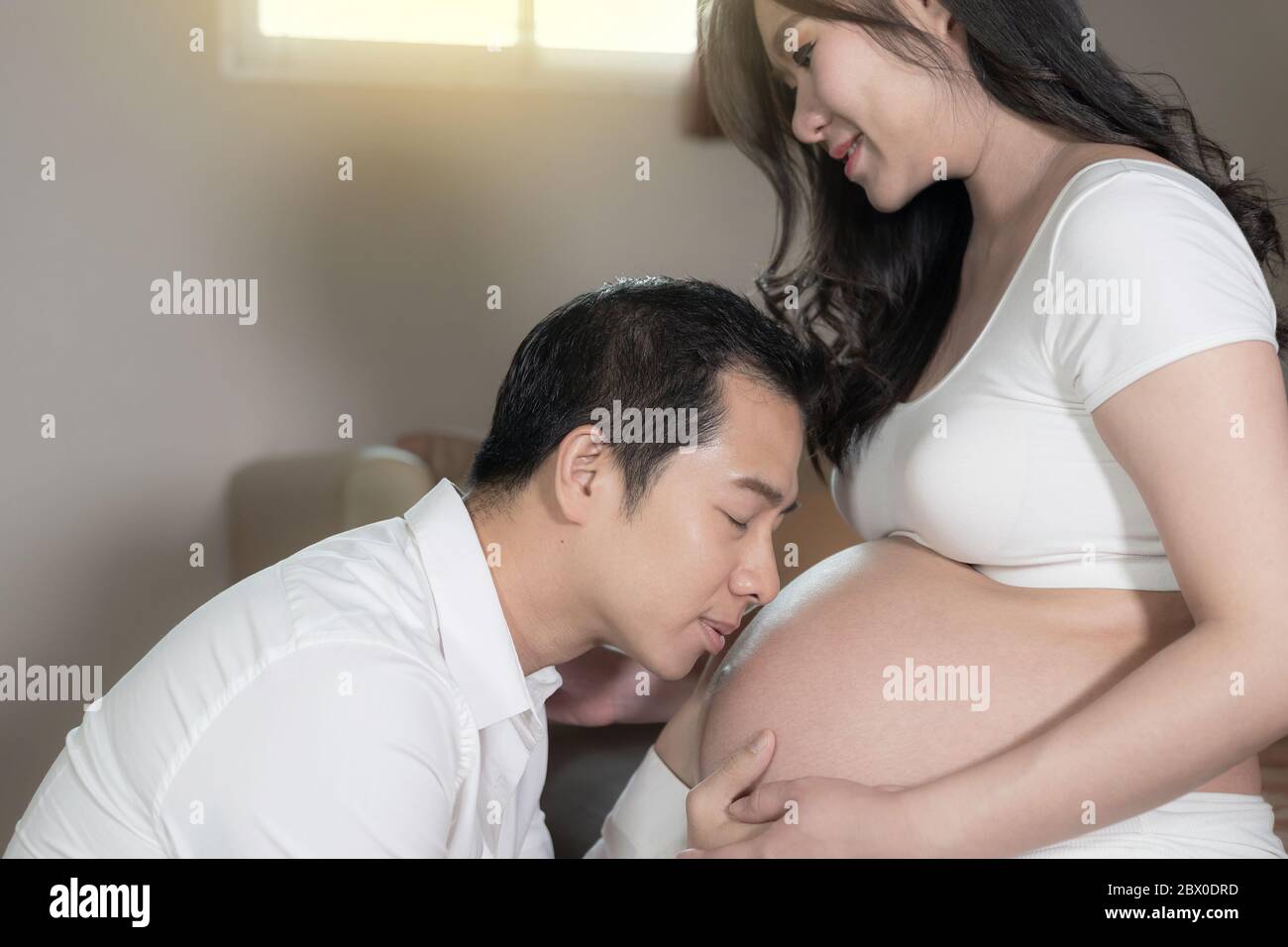 Asian couple femme enceinte et mari, baiser sur le ventre de femme de  chambre à l'arrière-plan Photo Stock - Alamy