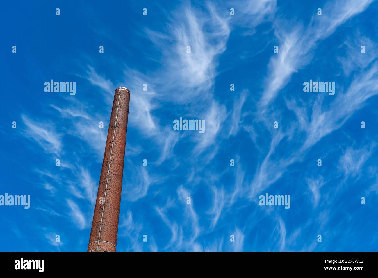 Ciel bleu avec des nuages cirrus, nuages de glace en filigrane à haute altitude, annonciateurs de temps plus chaud, cheminées, émissions Banque D'Images