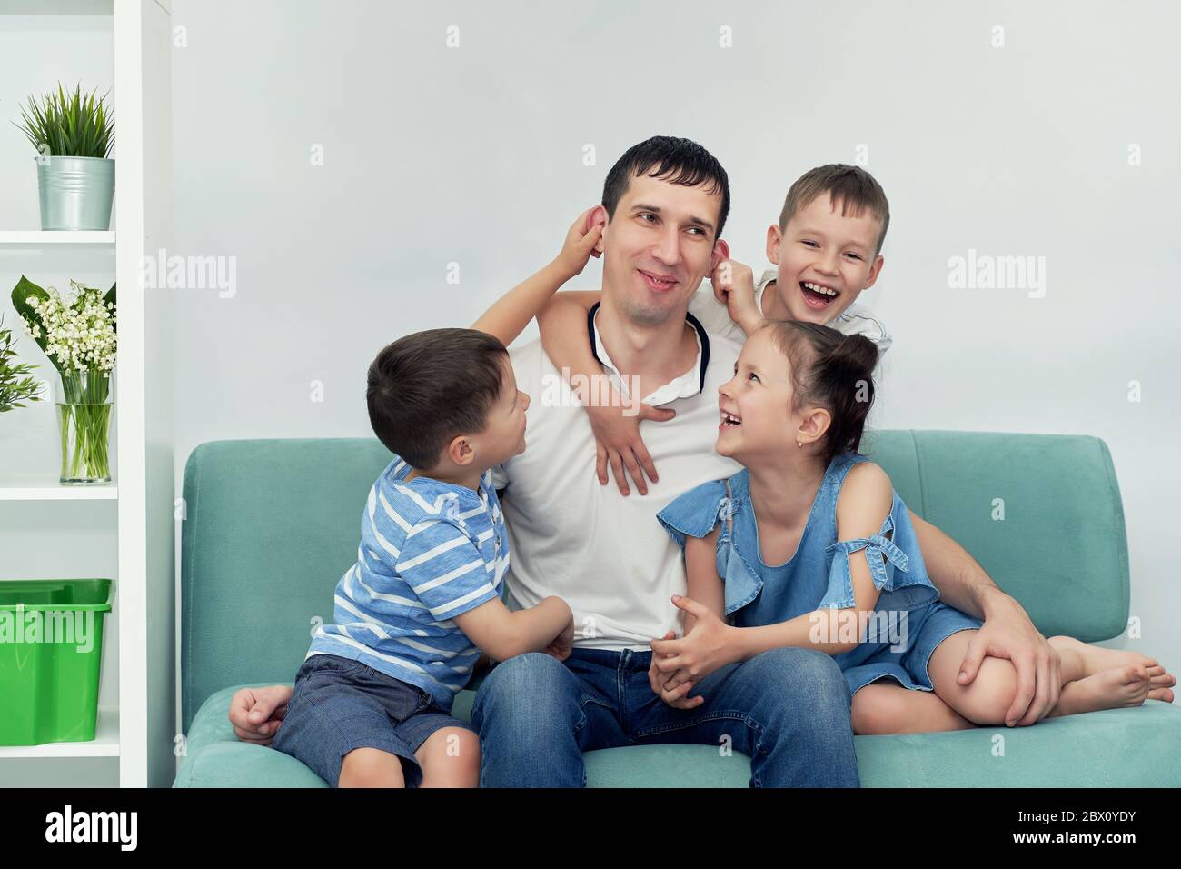 un père heureux avec beaucoup d'enfants et ses enfants est canapé bleu Banque D'Images