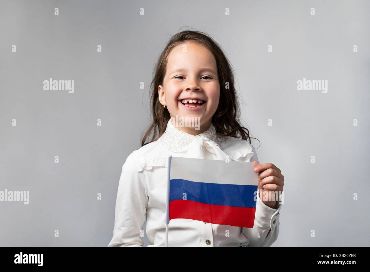 Une belle fille dans une chemise blanche tenant le drapeau de la Fédération de Russie. Banque D'Images