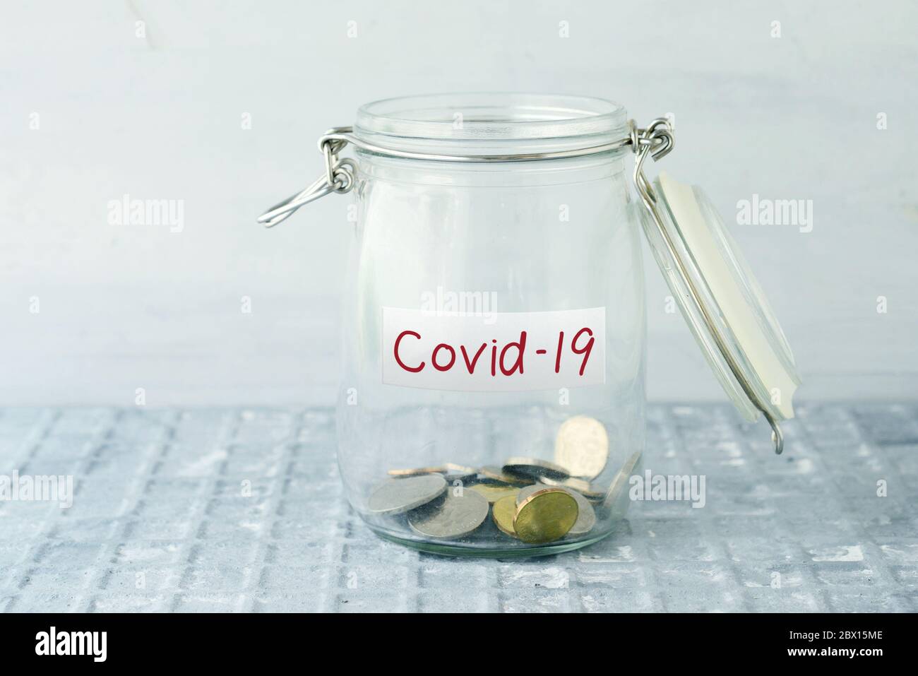 Pièces de monnaie en verre pot d'argent avec étiquette covid19, concept financier. Banque D'Images