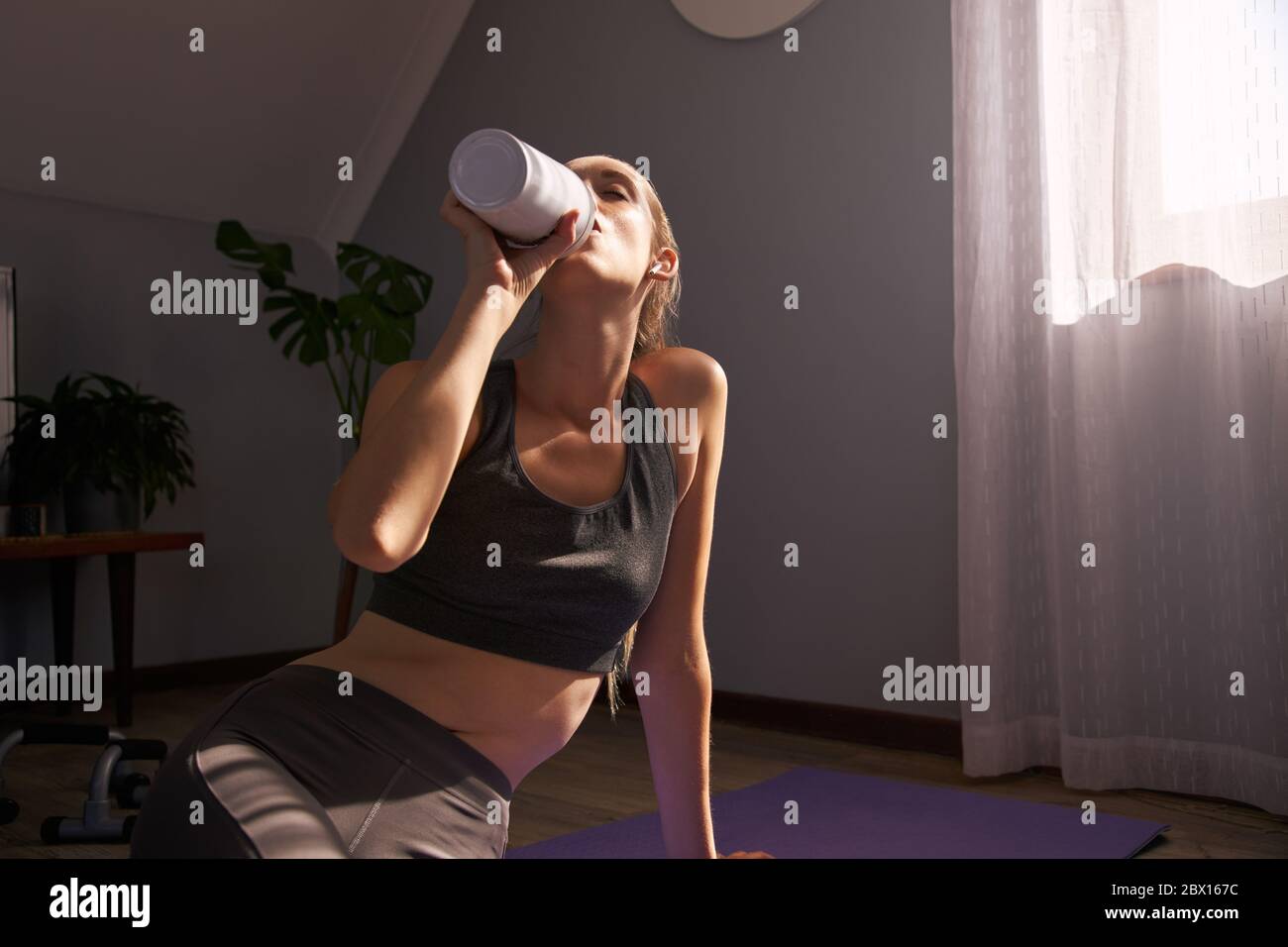 Femme buvant à partir de plastique bouteille d'eau libre après l'exercice à la maison. Banque D'Images