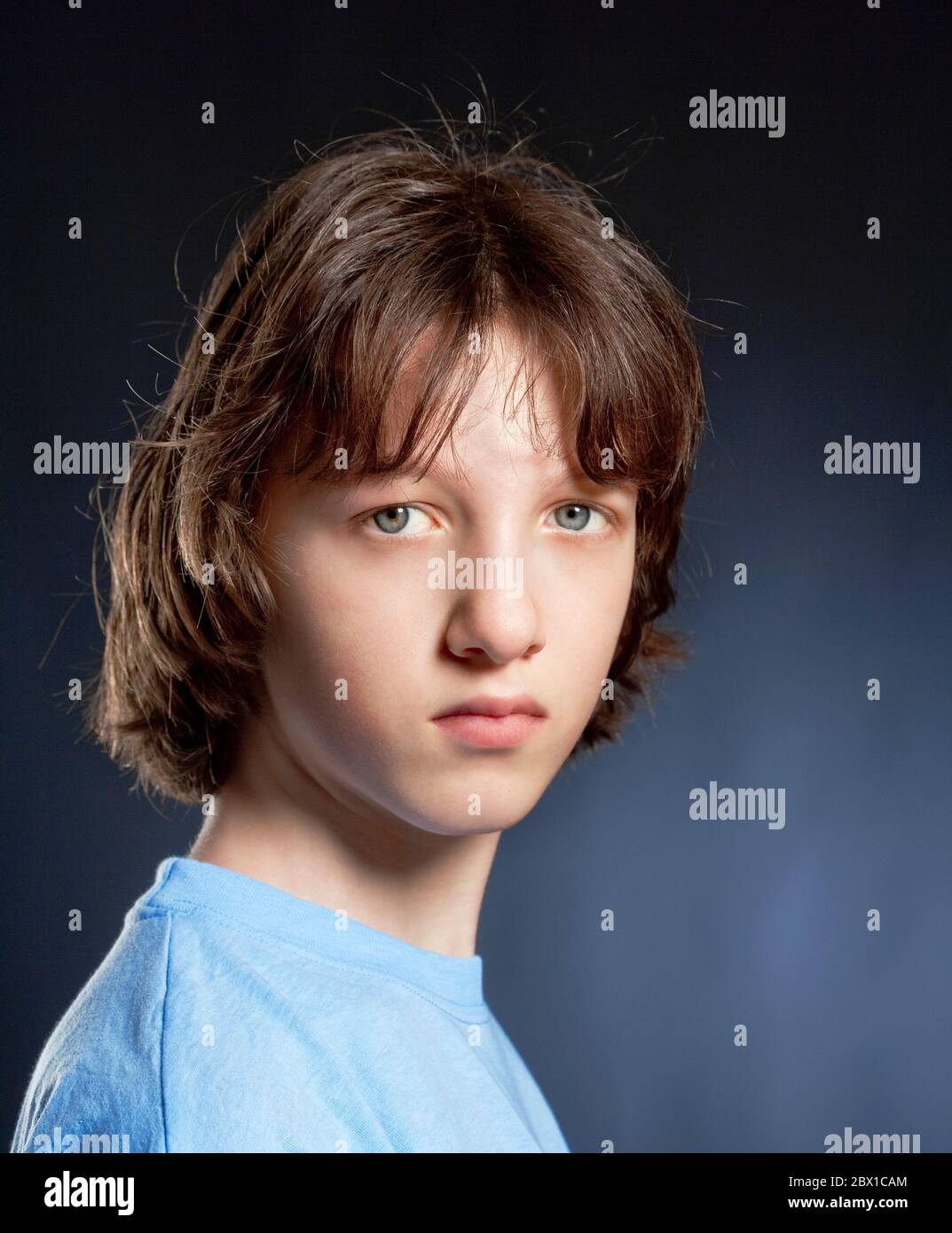 Portrait d'un garçon adolescent avec des cheveux bruns en dessus bleu. Banque D'Images