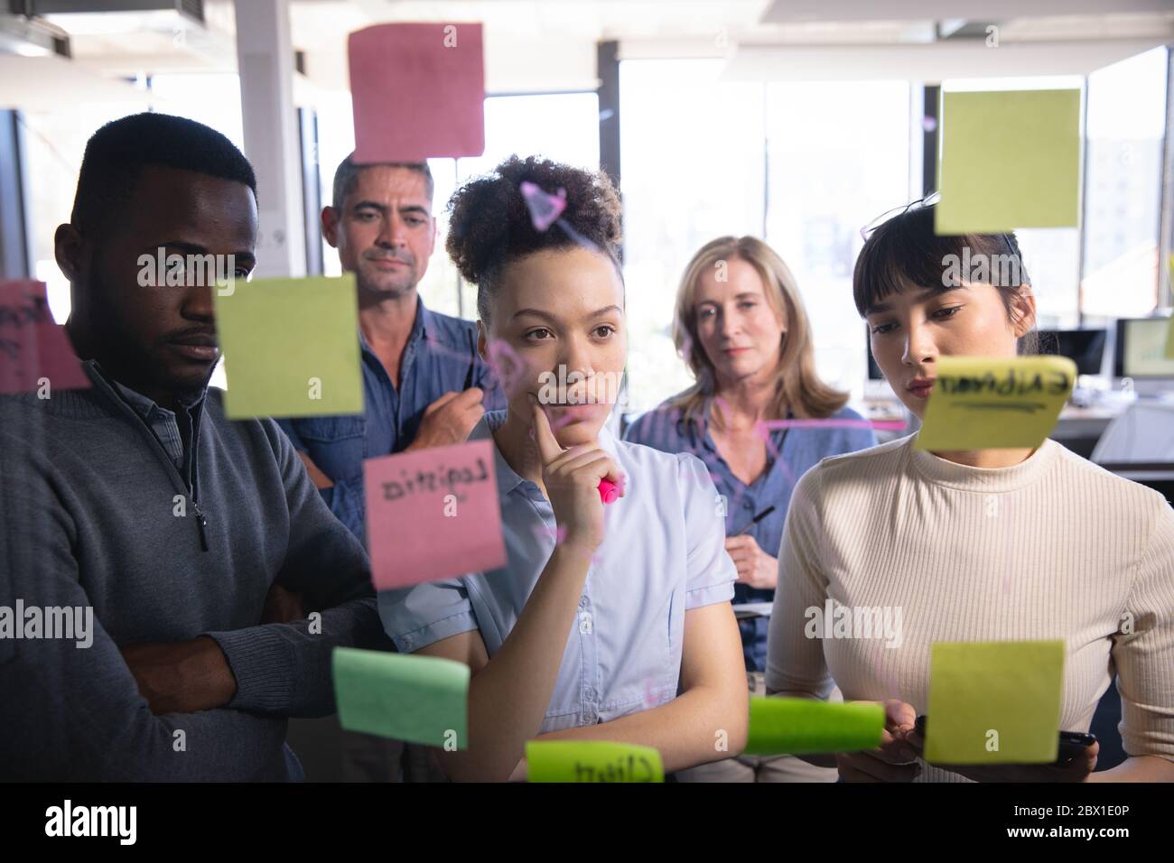 Les professionnels travaillent en collaboration au bureau à l'aide du tableau de post-informatique Banque D'Images