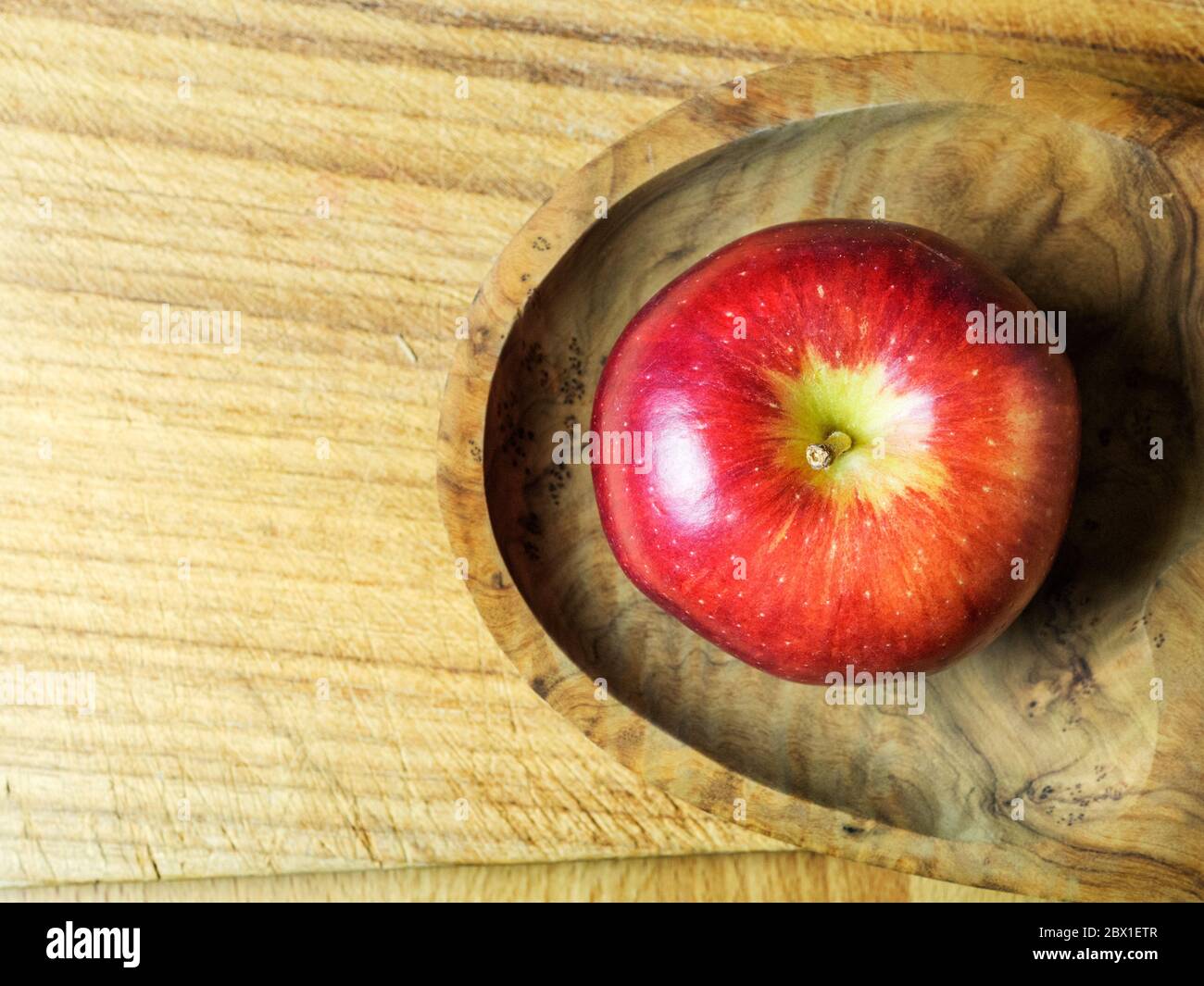 Une seule pomme de Braeburn mangeant dans un disque en bois sur une planche à découper avec un espace de copie Banque D'Images