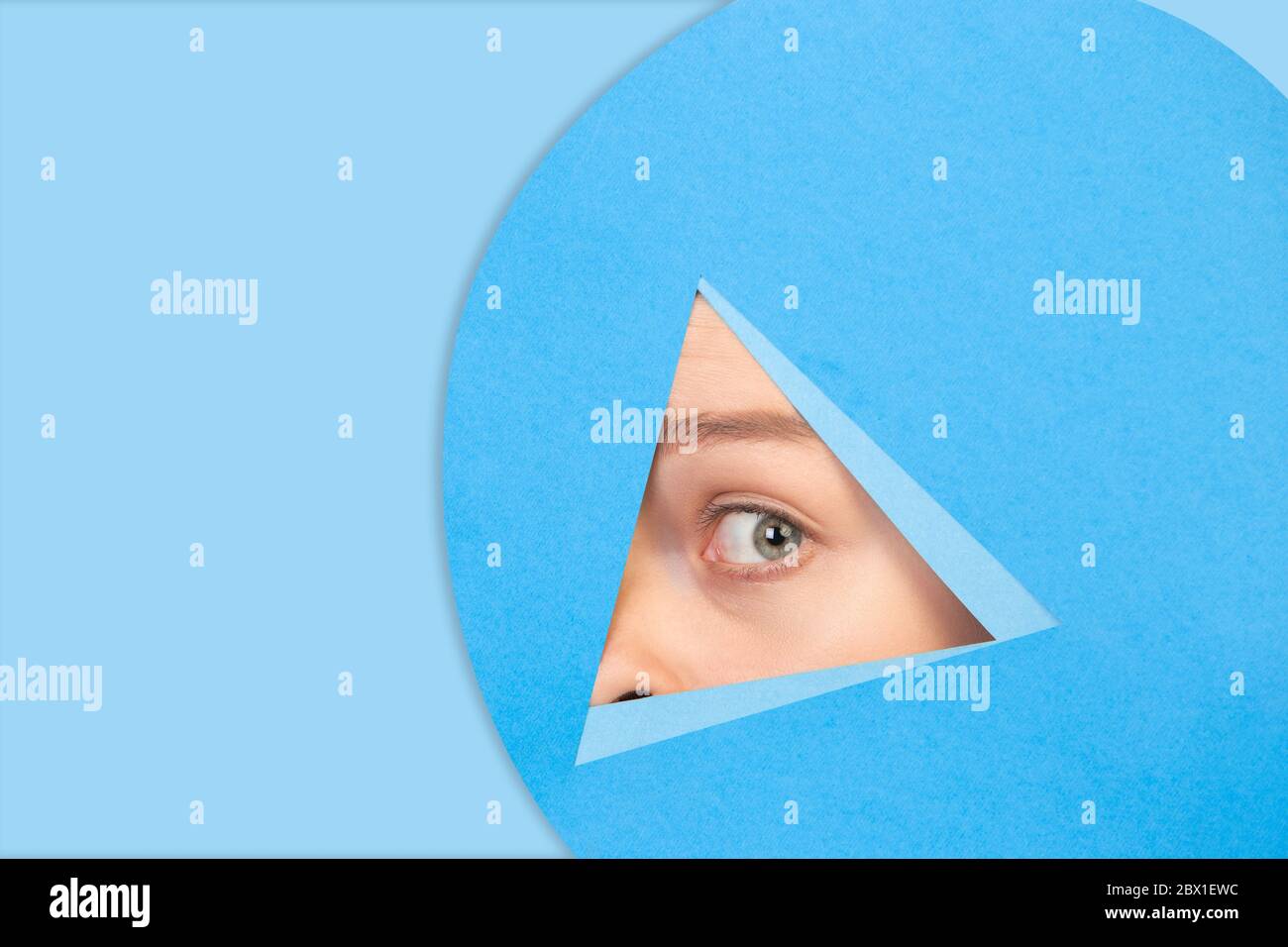 Gros plan des poireaux féminins, regarde à travers le triangle dans un fond bleu. Style géométrique tendance, espace de copie. Couleurs éclatantes. Émotion cachée, regarder. Vente, proposition, finance et concept commercial. Banque D'Images