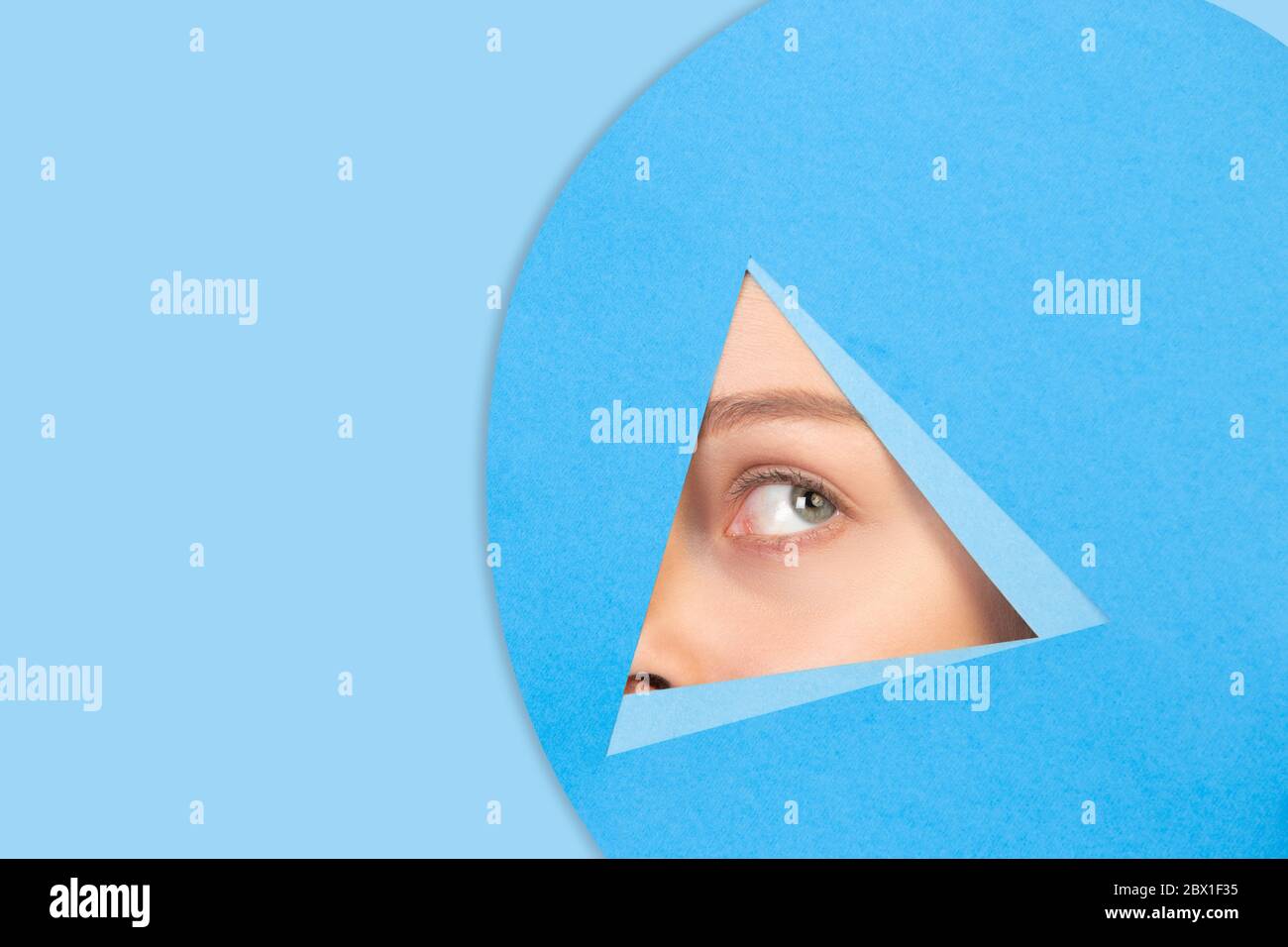 Gros plan des poireaux féminins, regarde à travers le triangle dans un fond bleu. Style géométrique tendance, espace de copie. Couleurs éclatantes. Émotion cachée, regarder. Vente, proposition, finance et concept commercial. Banque D'Images