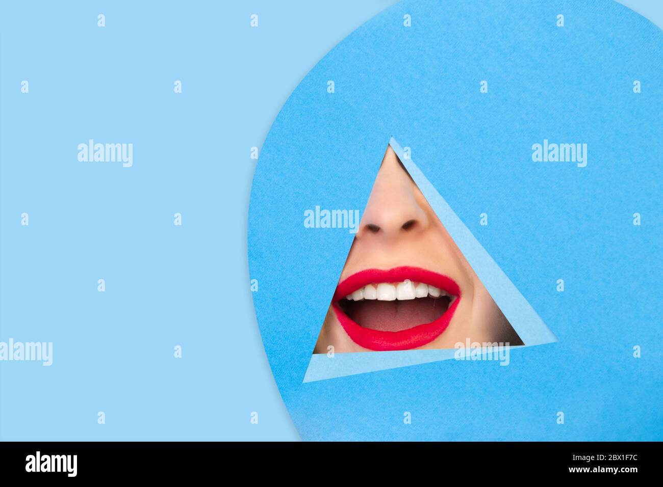 Génial. Gros plan femelle rouge lèvres peeks à travers le triangle dans fond bleu. Style géométrique tendance, espace de copie. Couleurs éclatantes. Émotion cachée, maquillage. Vente, proposition, finance et concept commercial. Banque D'Images