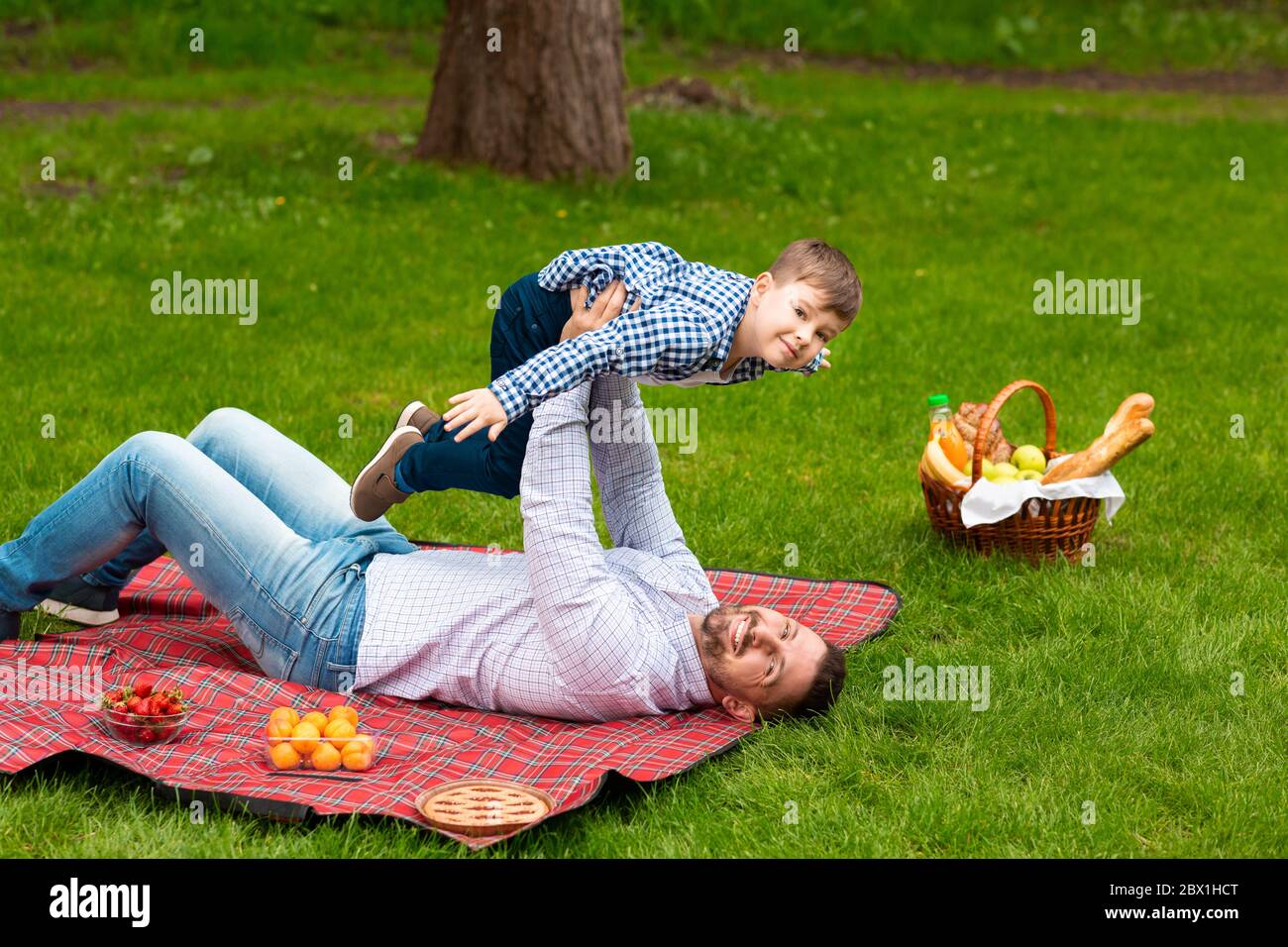 Papa joyeux jouant avec son enfant pendant le pique-nique sur la prairie verte, espace de copie Banque D'Images